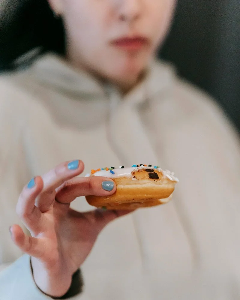 girl holding iced donut in hand