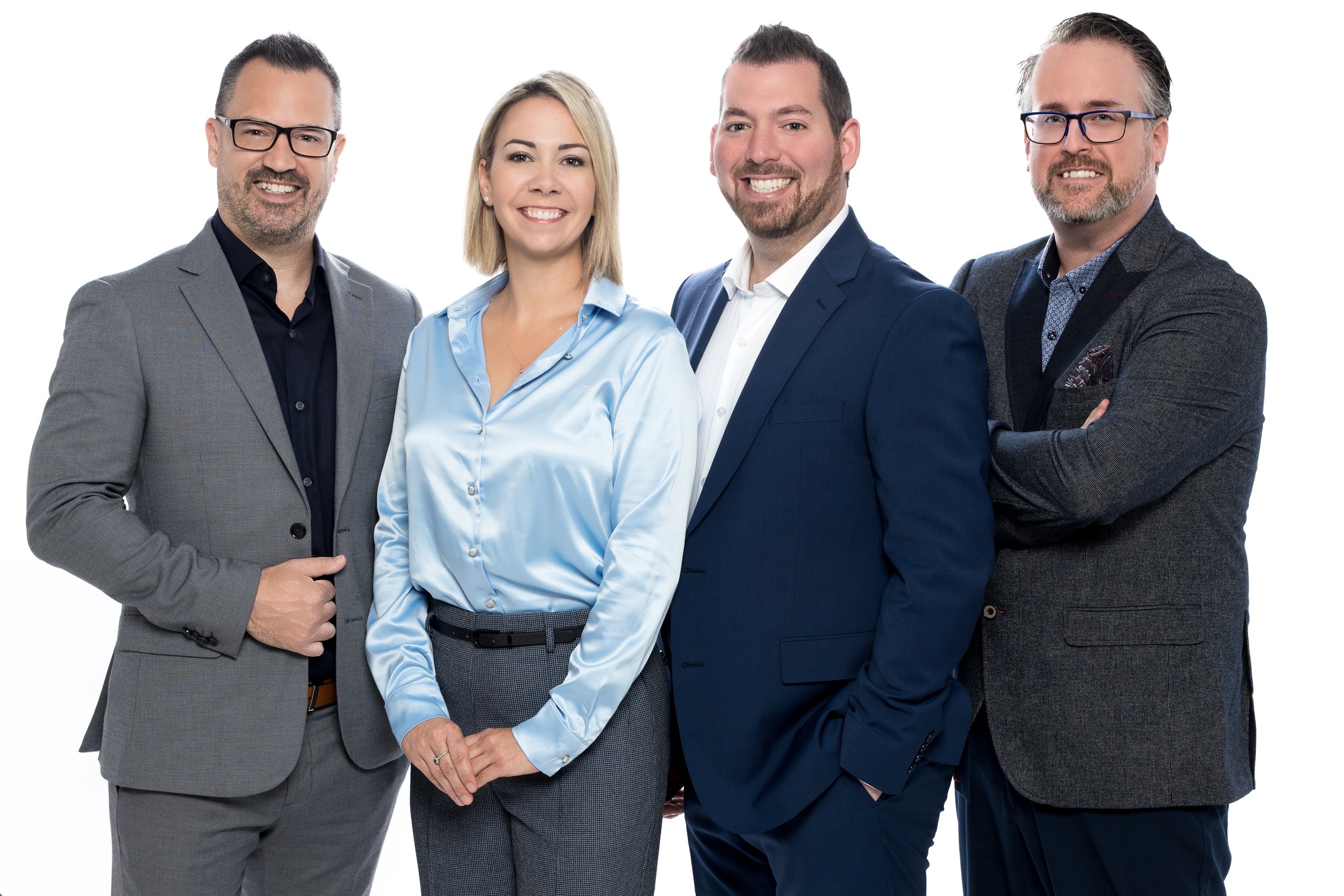 Photo d'équipe de travail - Groupe de quatre personnes d'affaires souriantes, habillées en vêtements professionnels, posant contre un fond blanc.