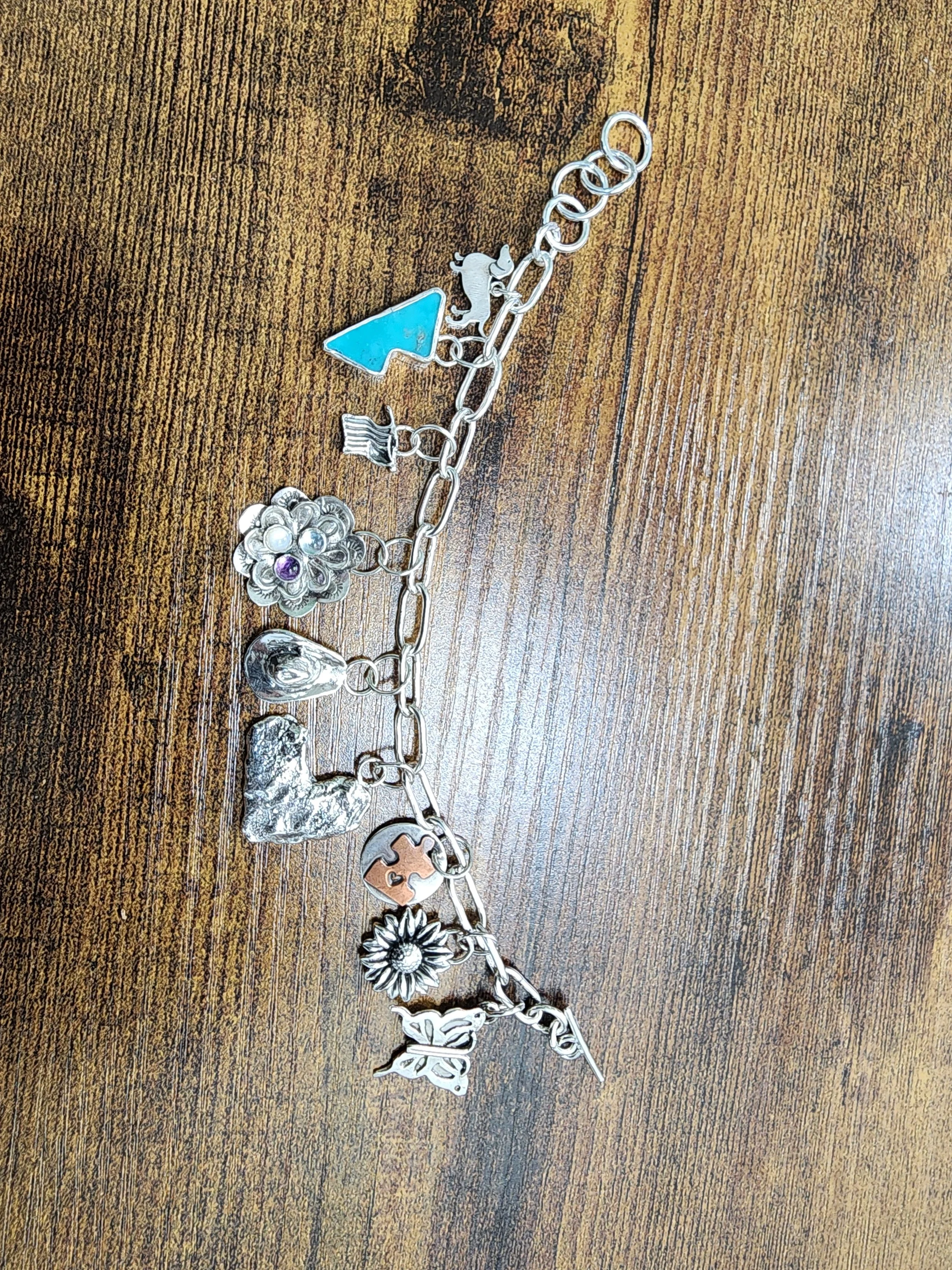 Custom charm bracelet with hand fabricated sterling silver chain and multiple handmade charms. Highlights unique, handmade artisan jewelry and personalized design for custom orders.