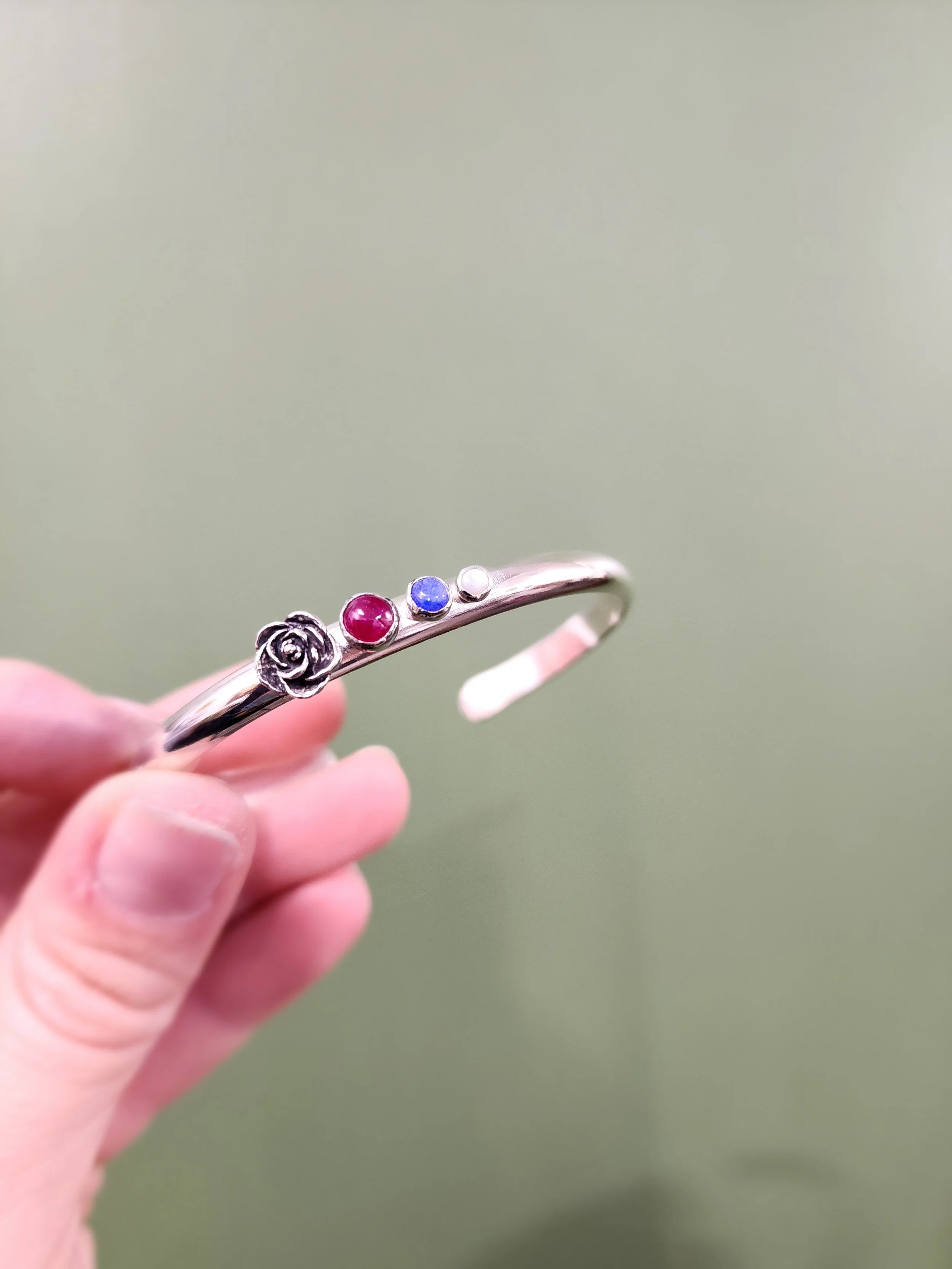 Sentimental custom sterling silver bracelet with birthstones. Handmade by Fire and Fringe, showcasing heirloom-quality artisan jewelry.