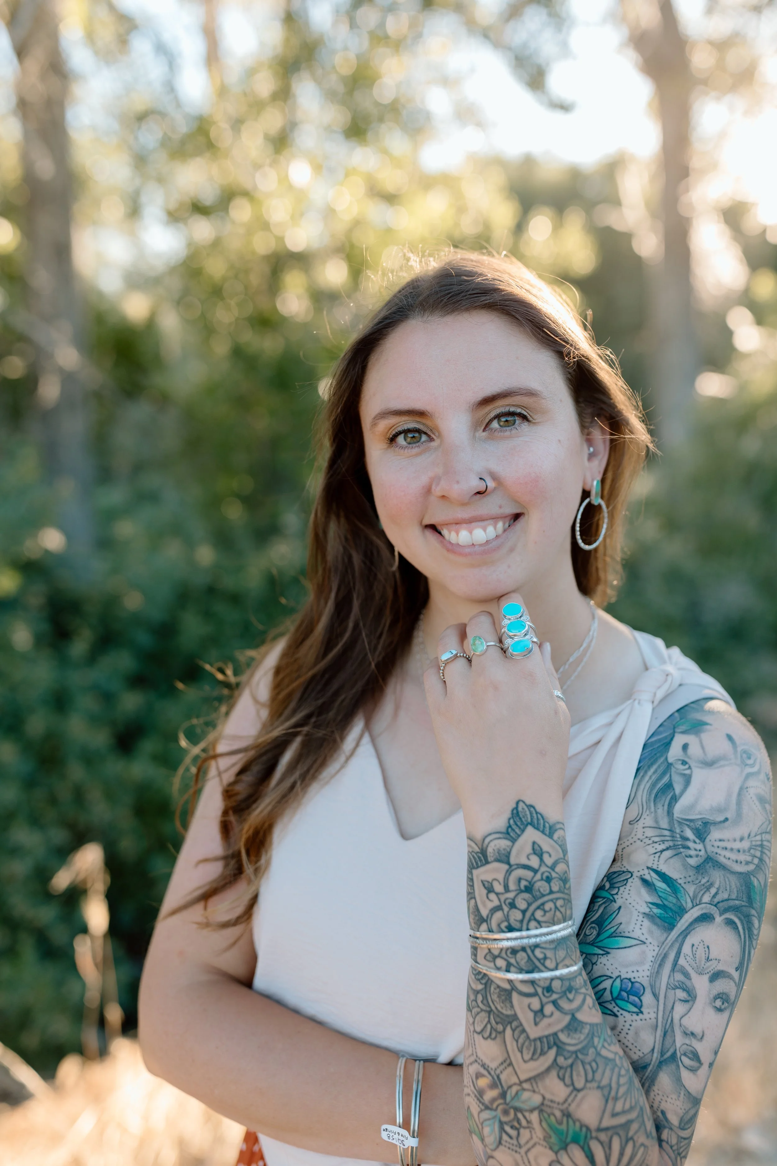 Lifestyle photo of a woman wearing handmade sterling silver jewelry and turquoise pieces from Fire and Fringe. The image features artisan silver rings, necklaces, and earrings styled in a casual, modern setting, highlighting the unique craftsmanship.