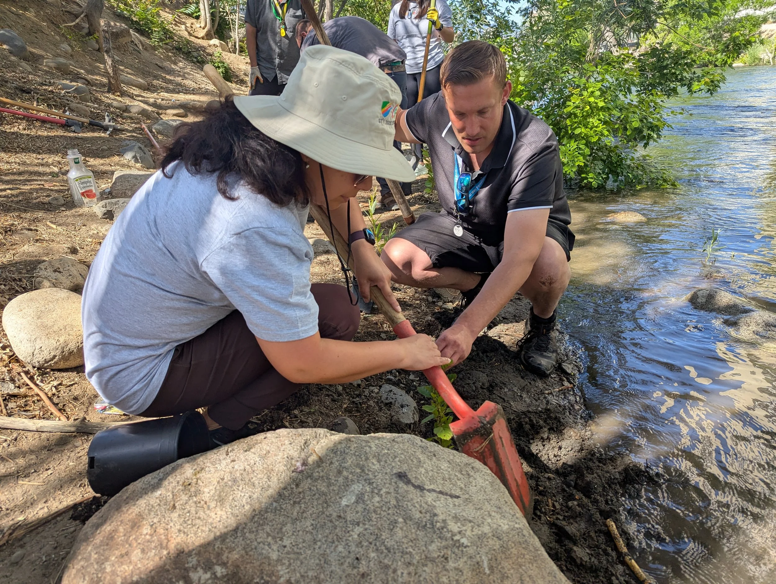man and woman with shovel planting a tree along the truckee river's urban corridor