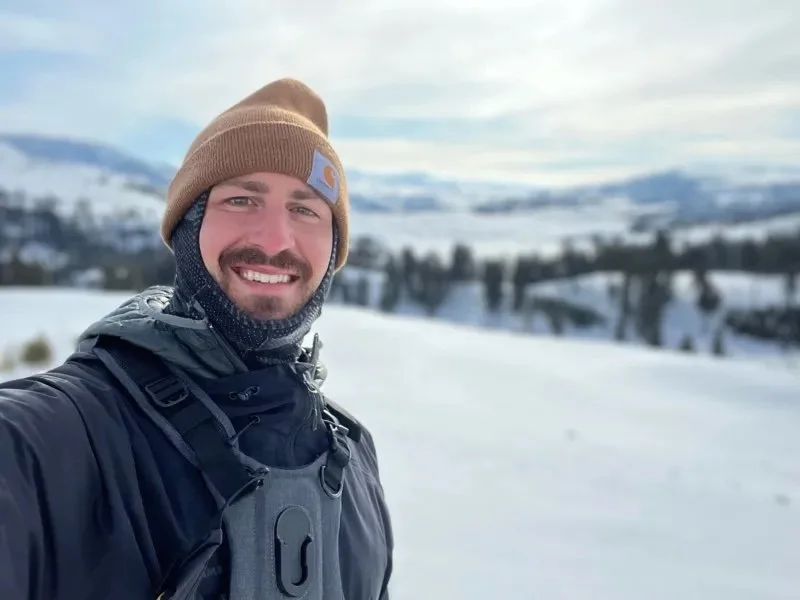 A man standing in a snowy landscape taking a selfie.