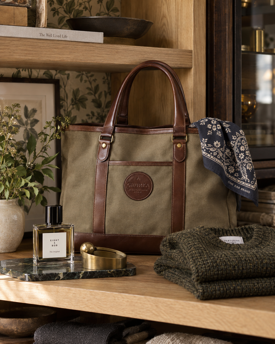 Ghurka canvas-and-leather tote, One Ear Brand bandana, Eight & Bob fragrance, Craighill brass object, and Peregrine knitwear displayed at Crockett & Co.