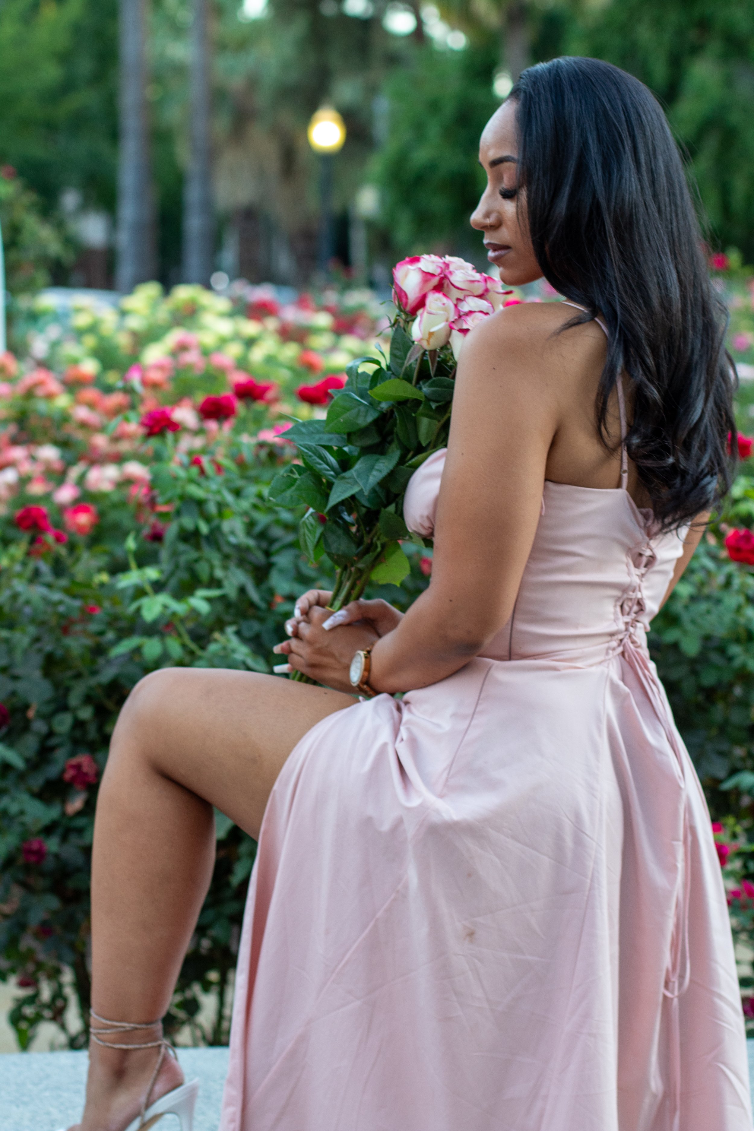 bouquet of roses, pink dress with left leg propped up on ledge