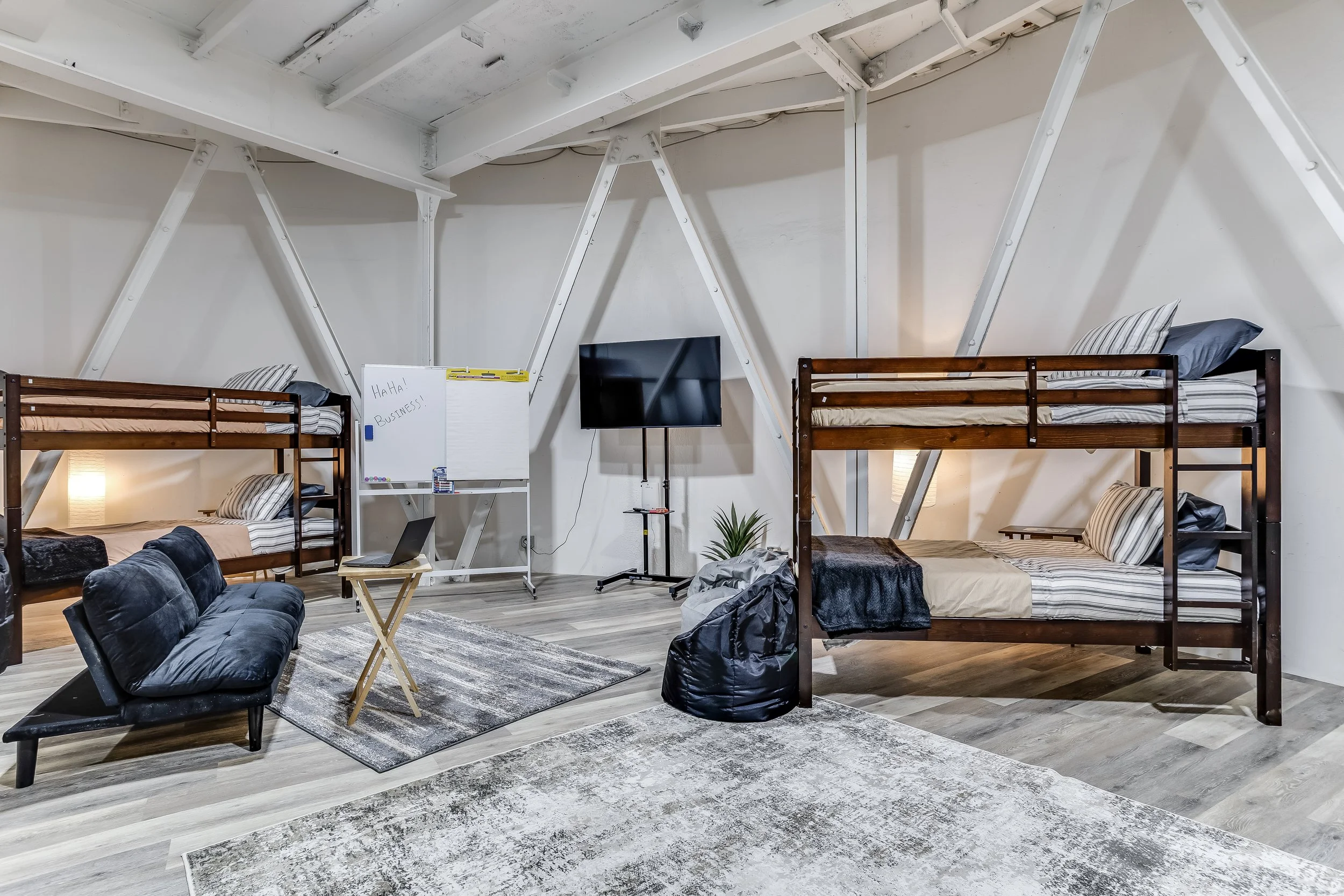 Underground bedroom with two queen beds and board games set against the silo's iconic curved concrete walls, ideal for group retreats.