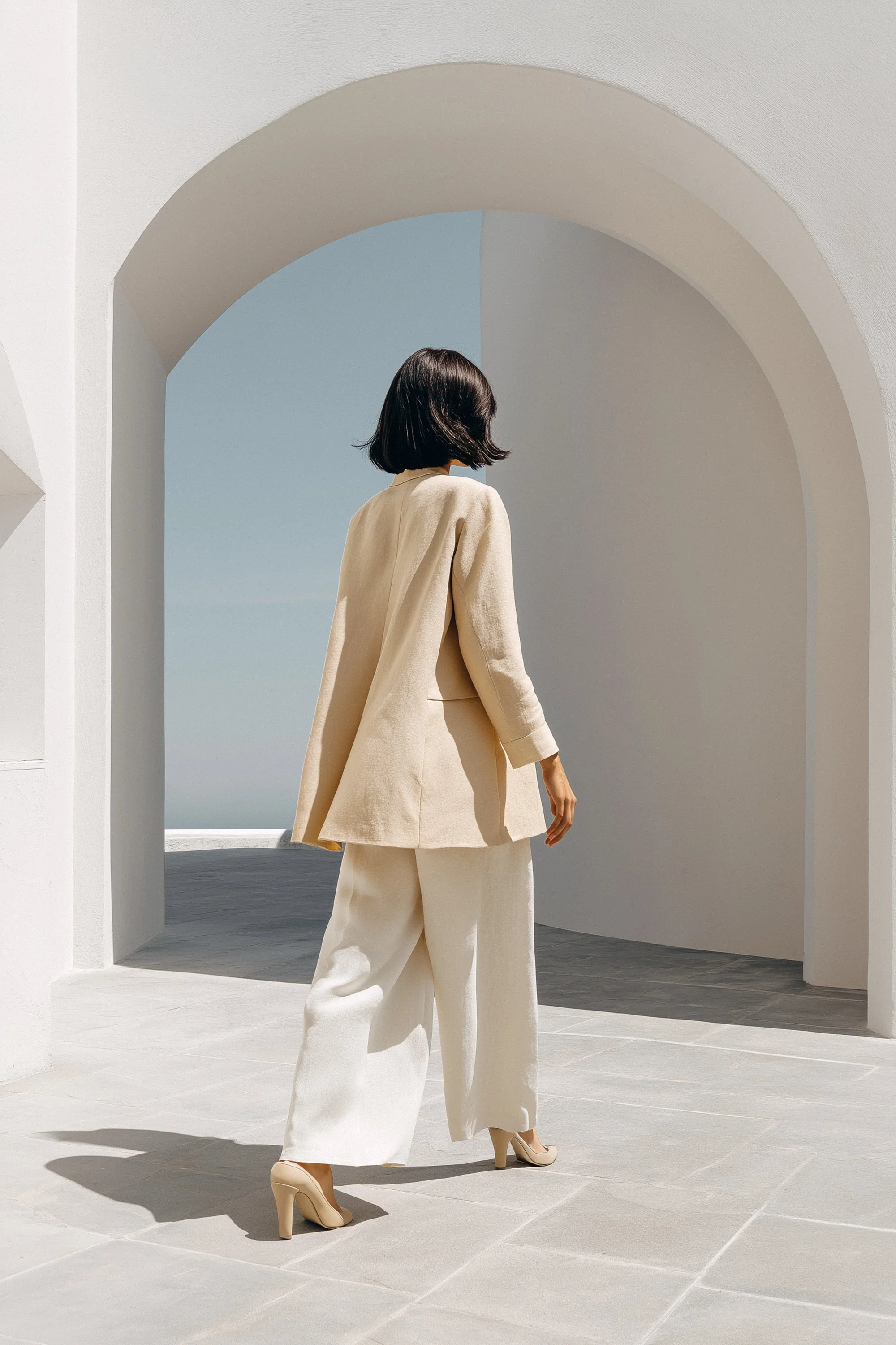 woman walking towards an arch with minimal beige styling