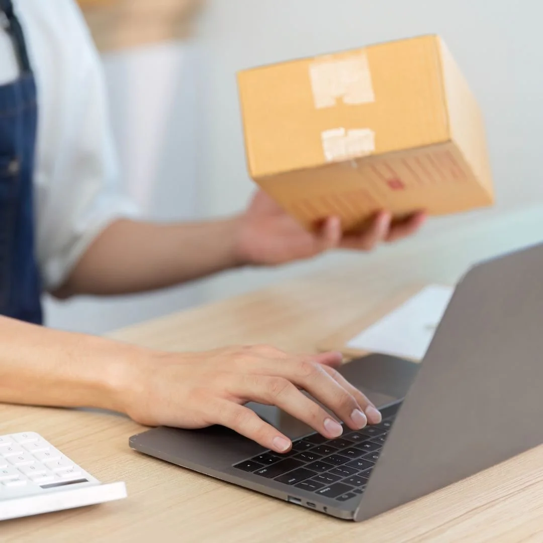 small shop owner packing products from an online sale with a computer