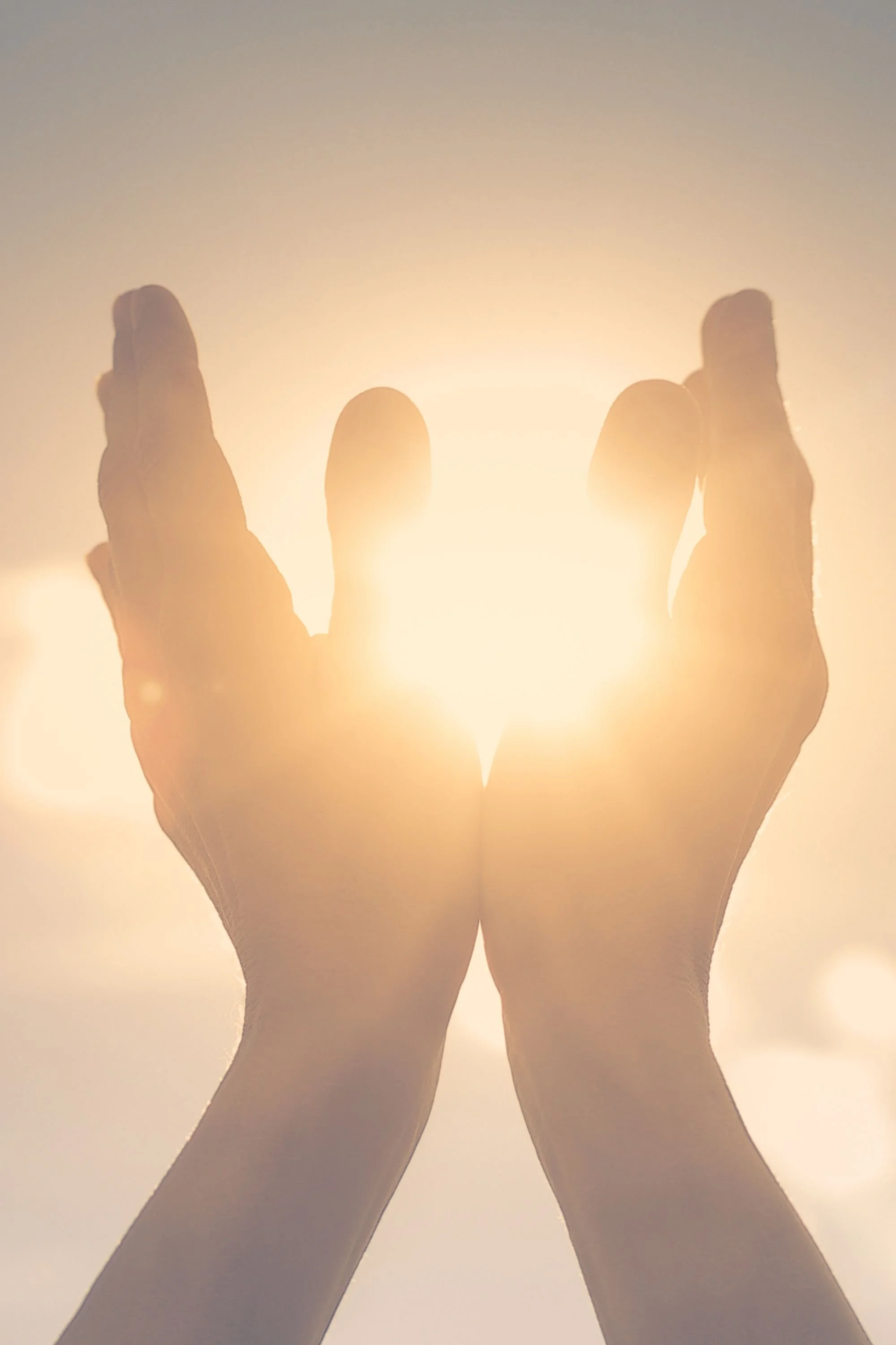 hands raised in the air with sun rays filtering through fingers