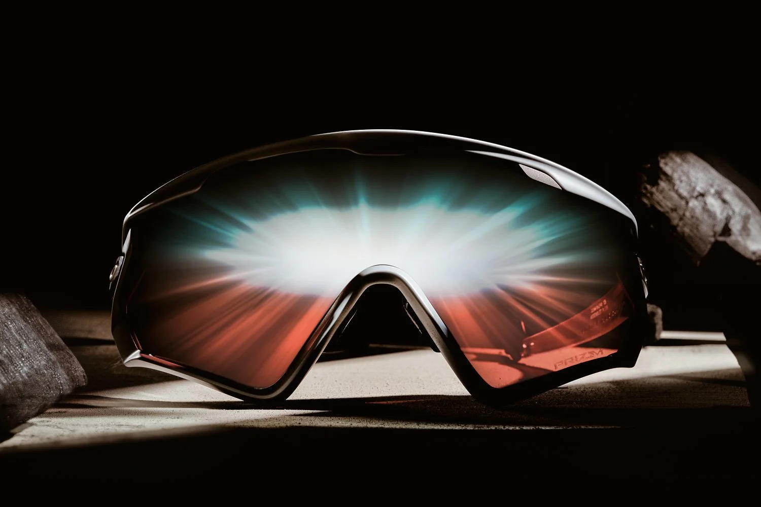 Close-up of high-tech sports sunglasses with reflective lenses displaying light reflections. Black background.