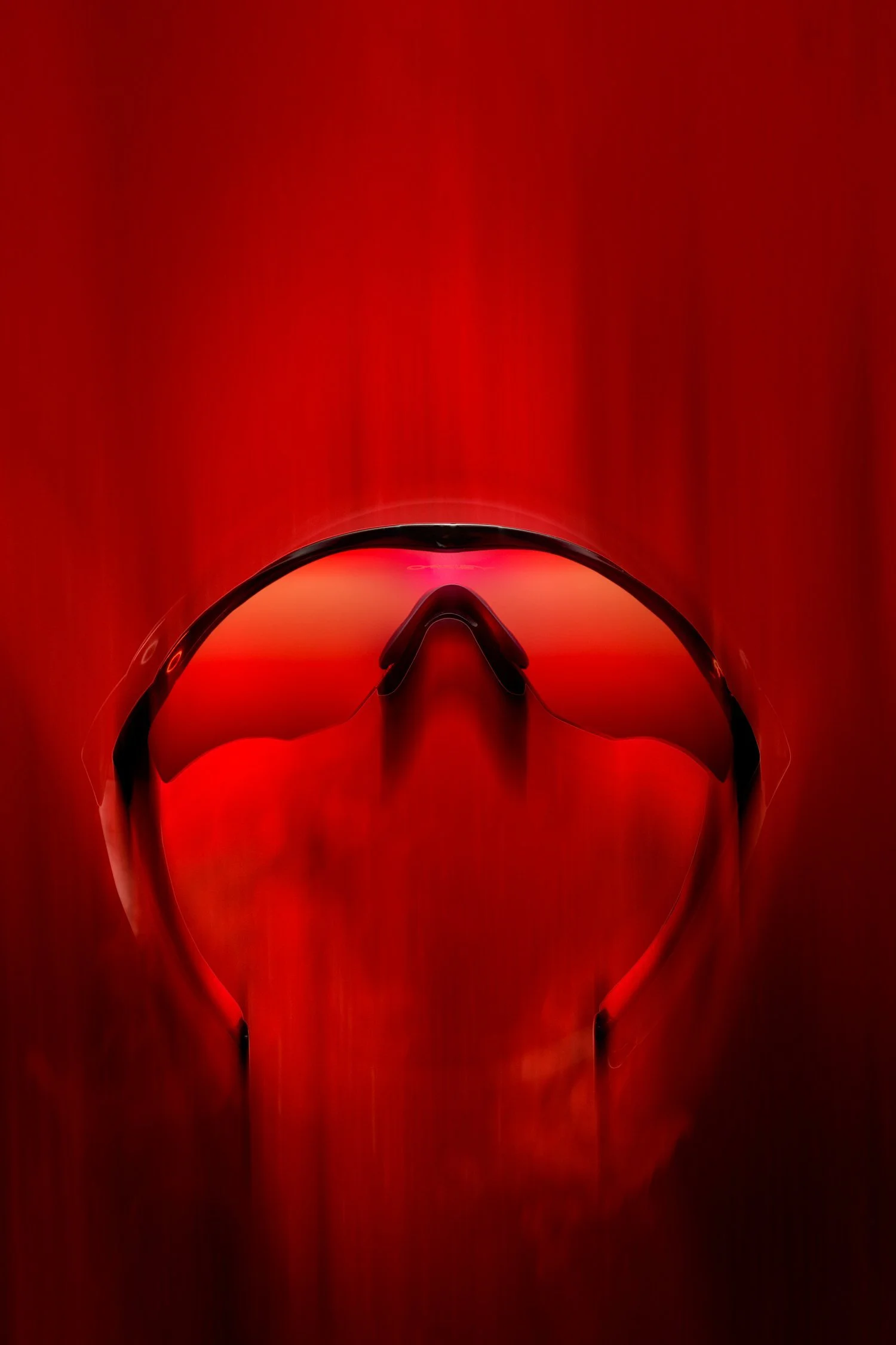 Red-lensed sports sunglasses on red background.