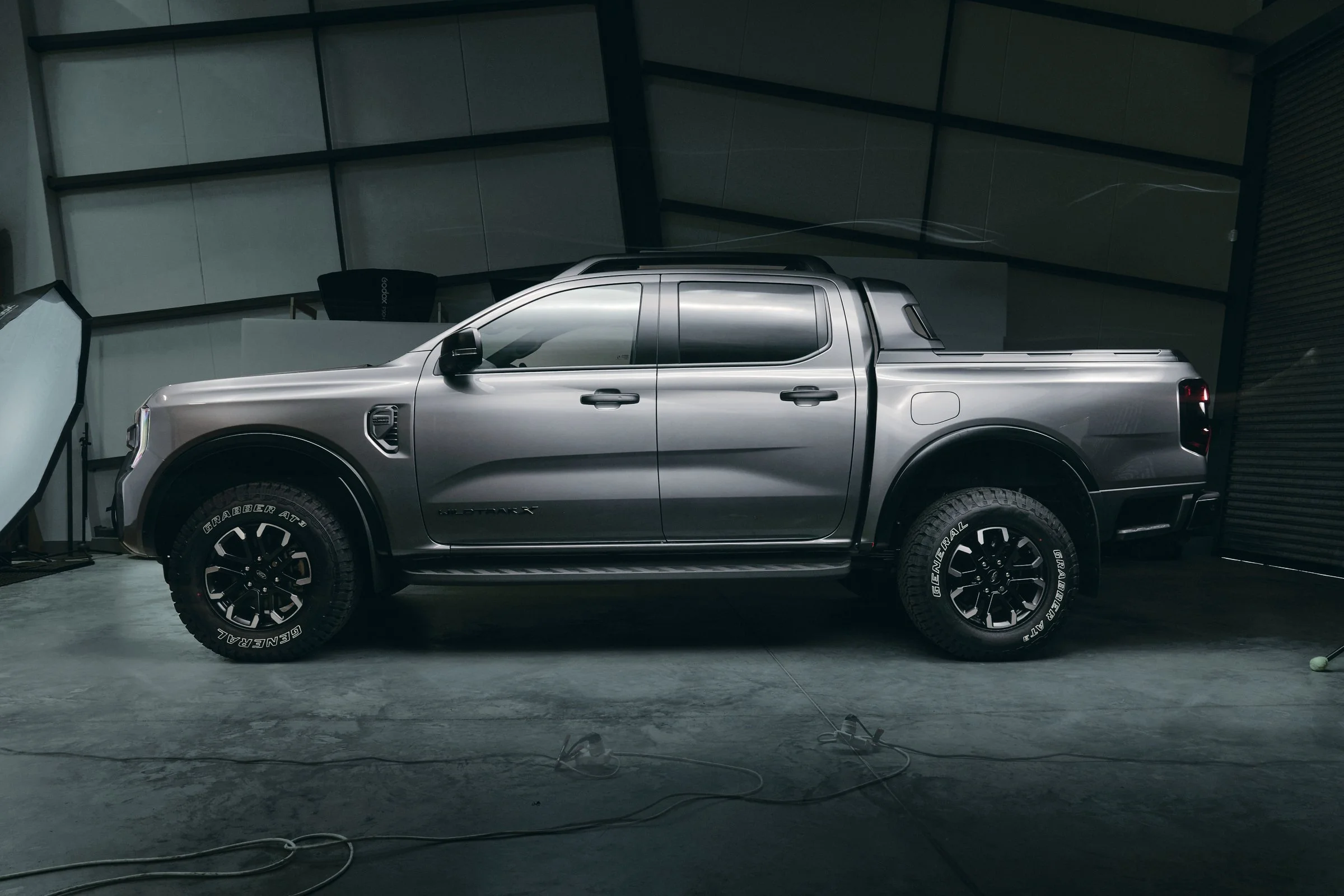 A silver Ford Wildtrak pickup truck is inside a photography studio with professional lighting equipment and a backdrop