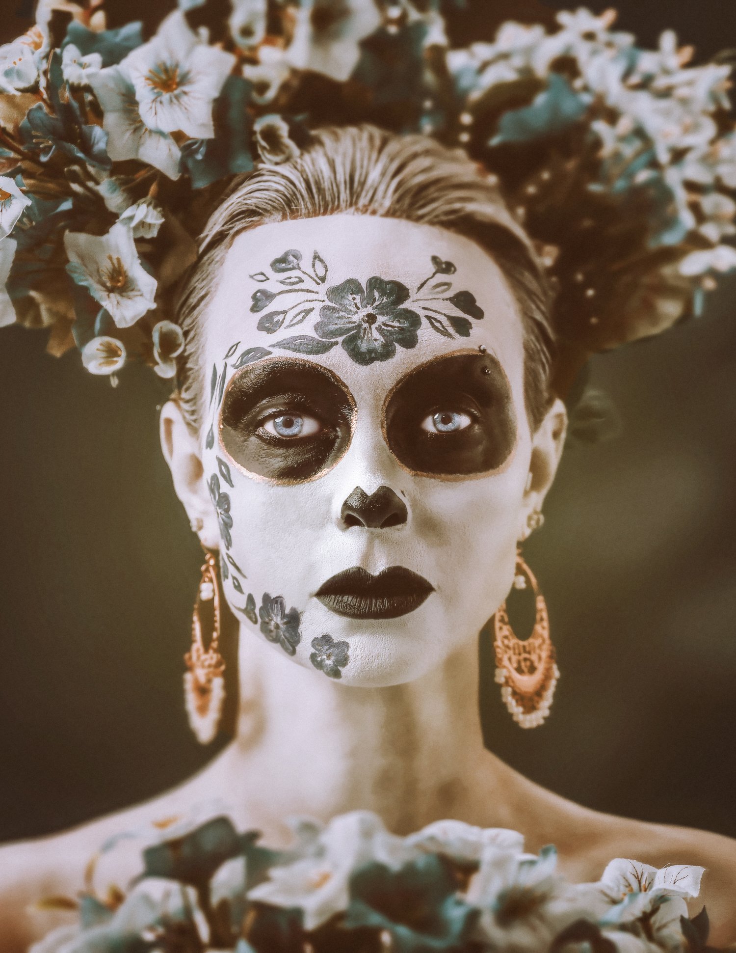 Editorial Photo of a model in Mexican Día de los Muertos makeup mixed with Delftware holding flowers. 