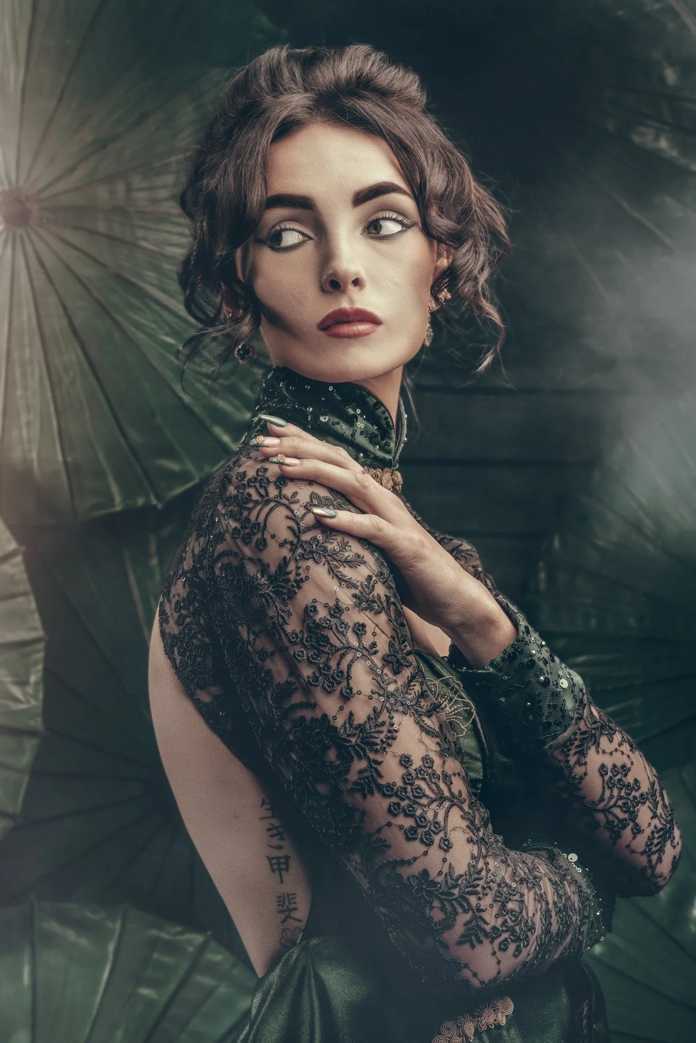 Woman in elegant lace dress, vintage style, with green parasols in background.