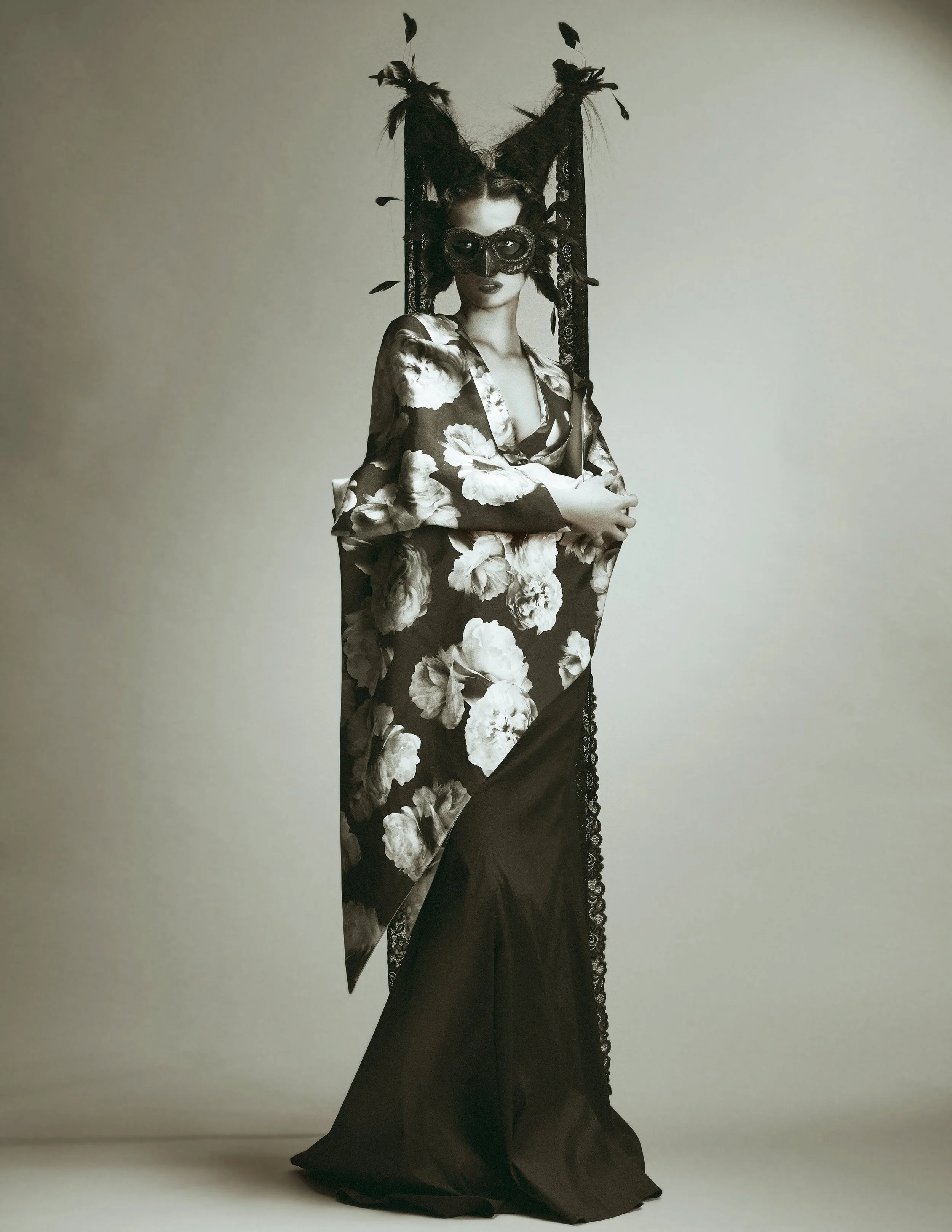 Fashion model wearing floral robe with mask and feathered headpiece