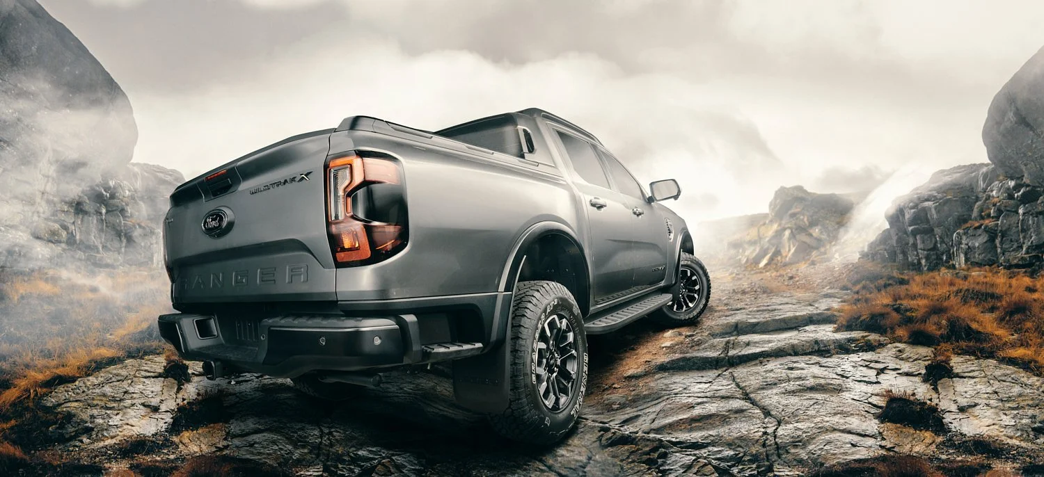 Gray pickup truck on rocky terrain with mountains in the background.