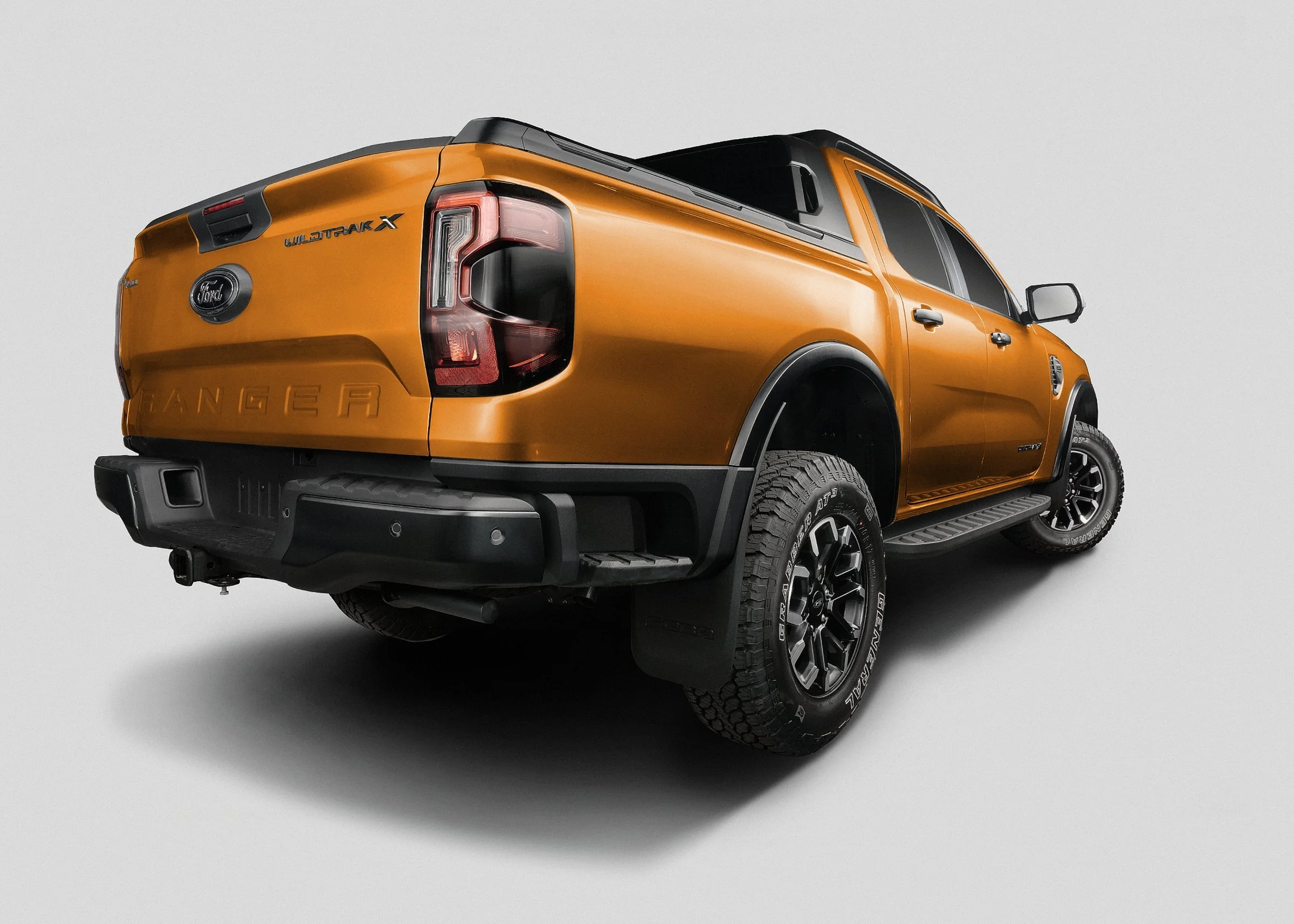 Orange Ford Ranger pickup truck viewed from the rear right side, with black accents and off-road tires, on a plain white background.