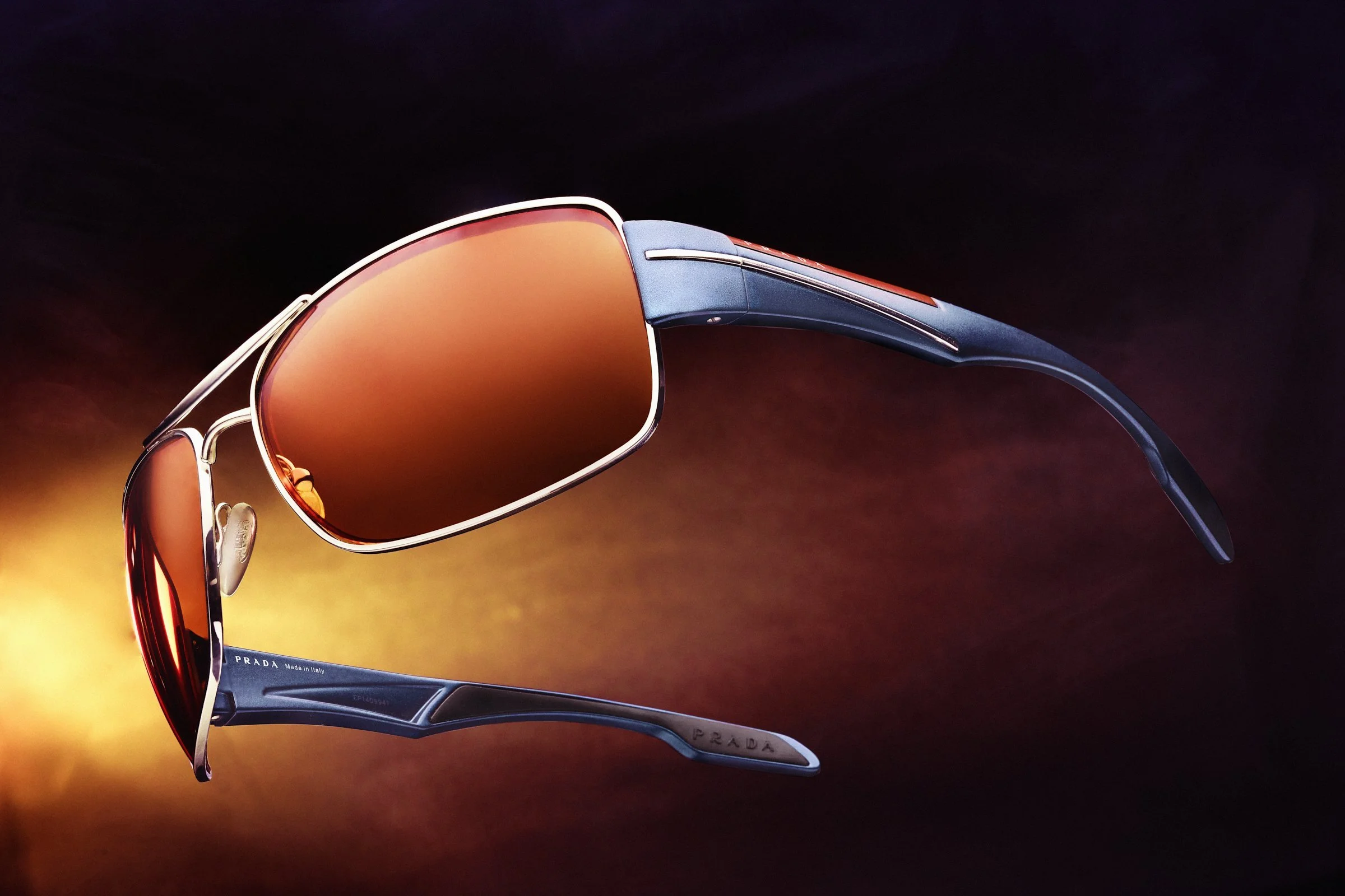 Designer sunglasses with brown lenses and metallic frames on a gradient background.