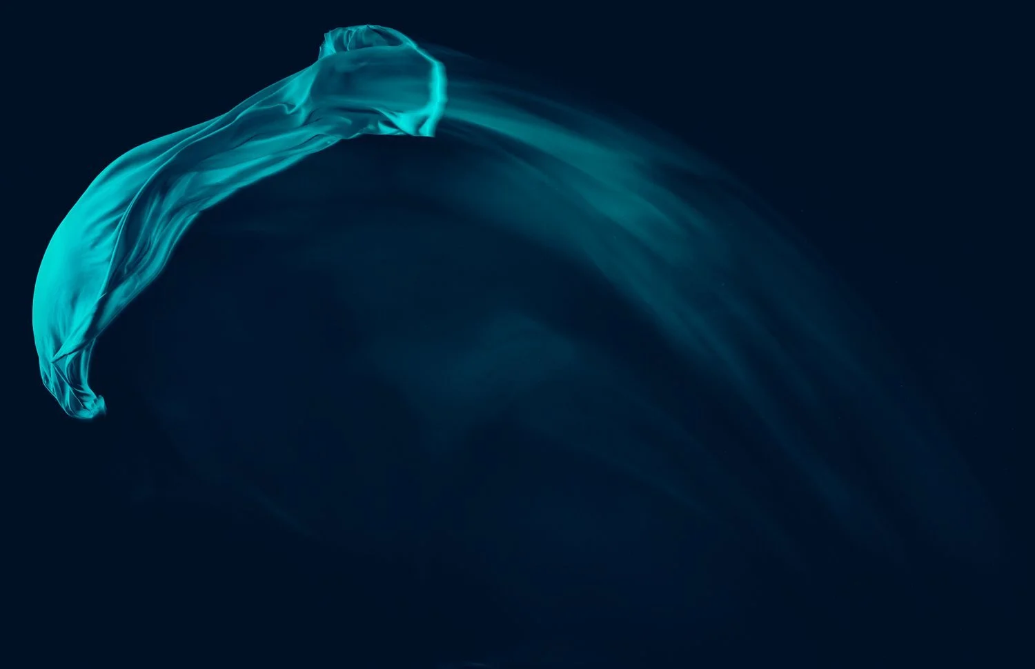 Flowing turquoise fabric against dark background