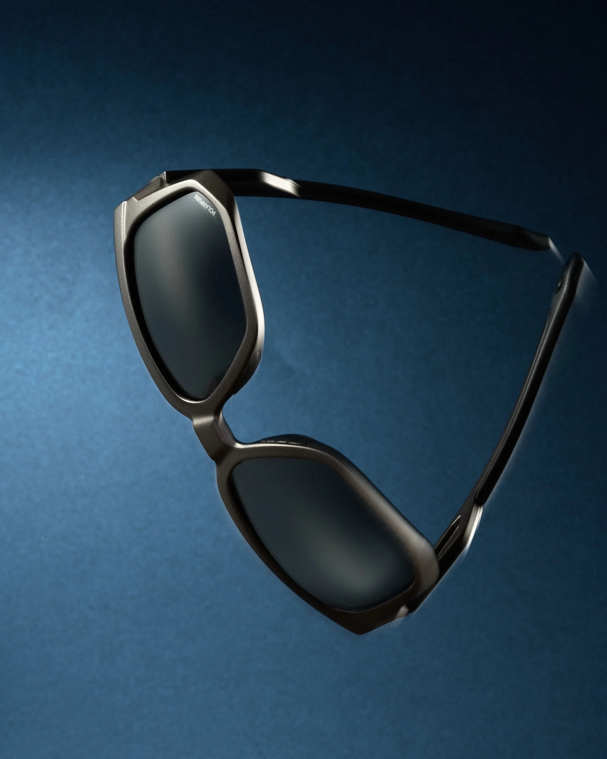 Black sunglasses with a modern design on a blue background with lighting highlight.