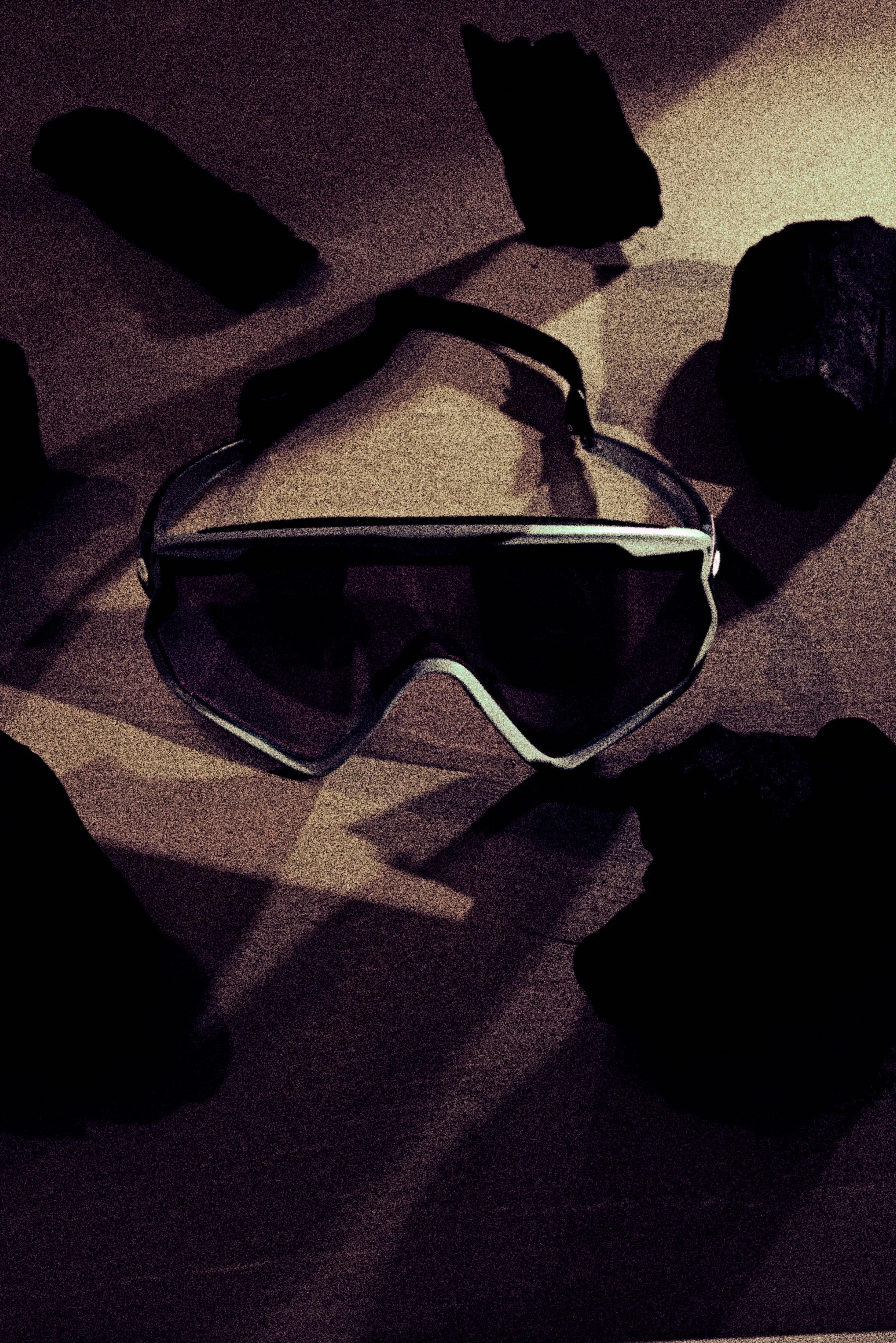 Goggles on a textured background with dark abstract shapes.