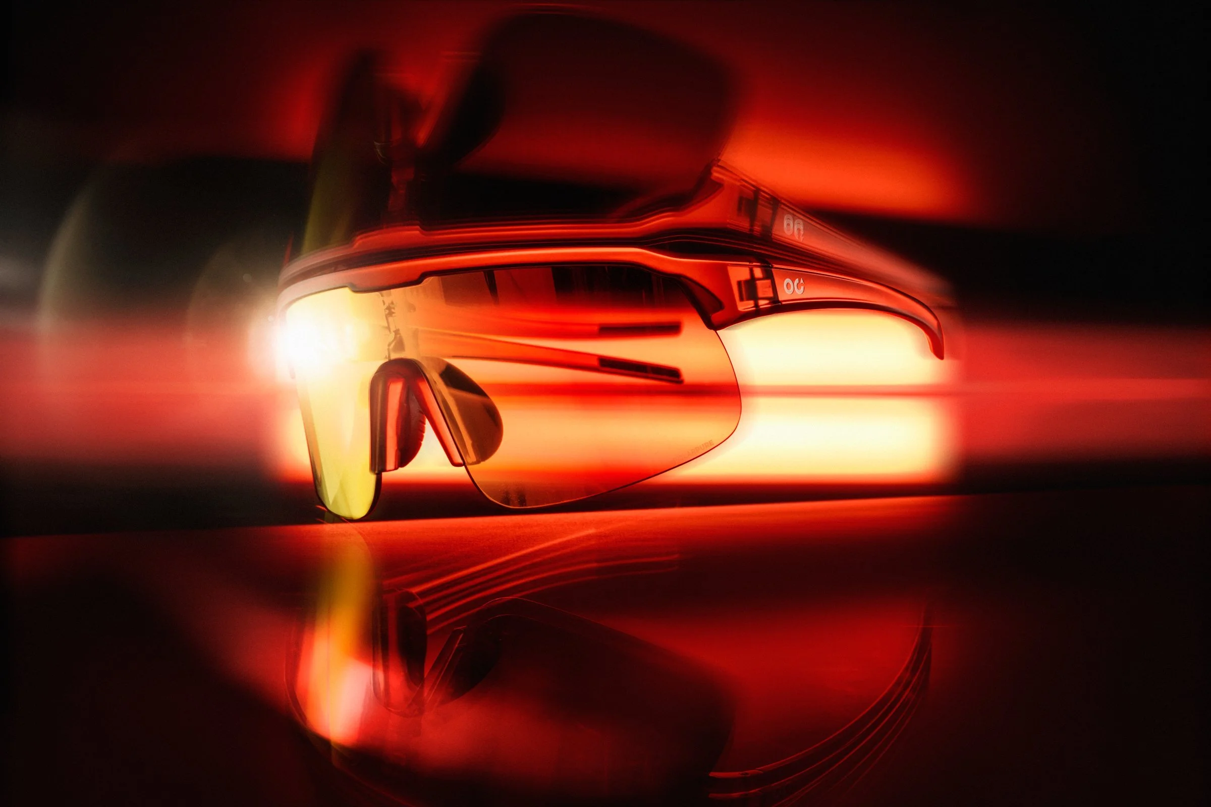 Futuristic sunglasses with reflective orange lenses illuminated in a dark setting with red and orange light streaks.