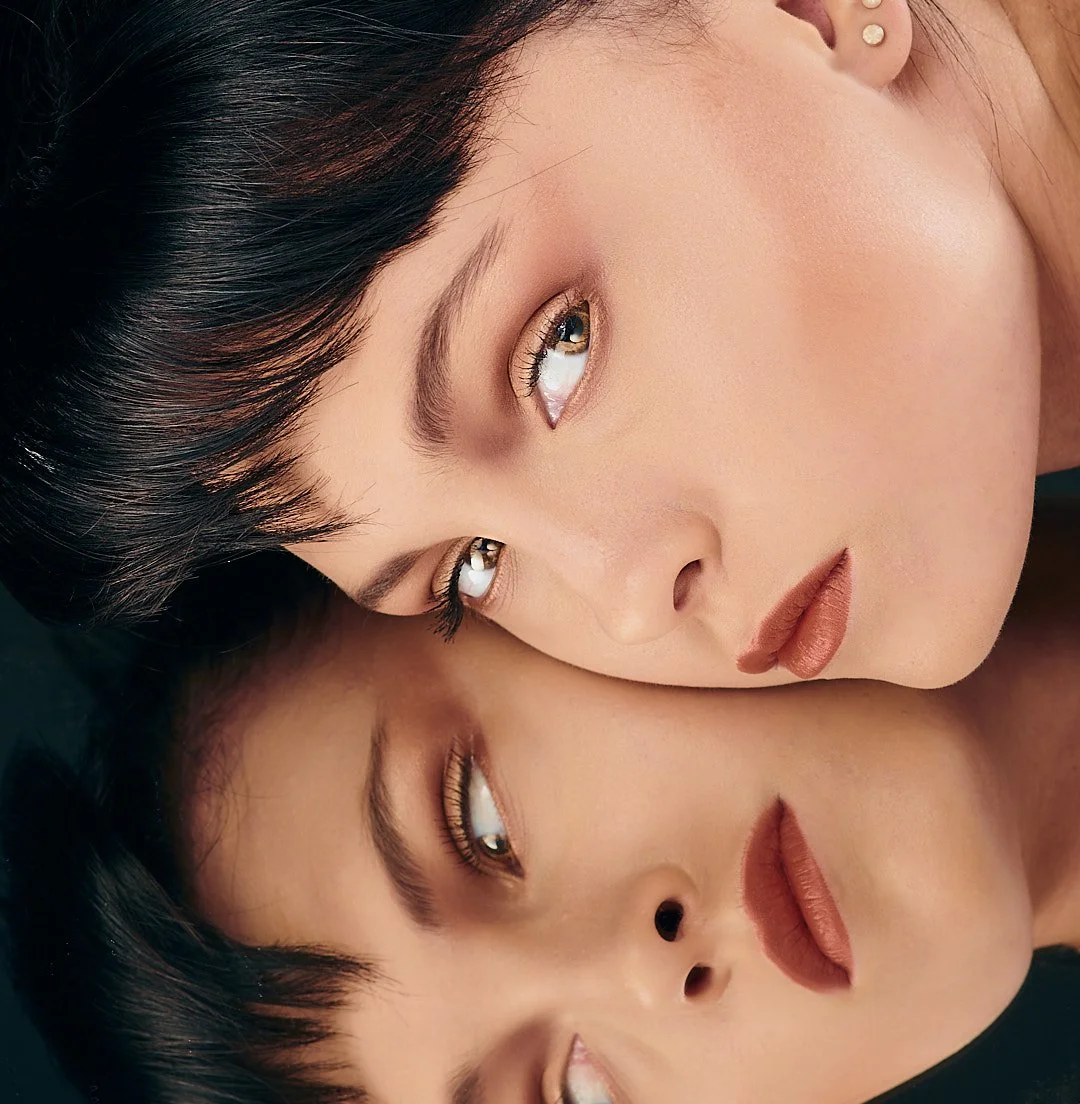 Woman with short hair reflected on a glossy surface.