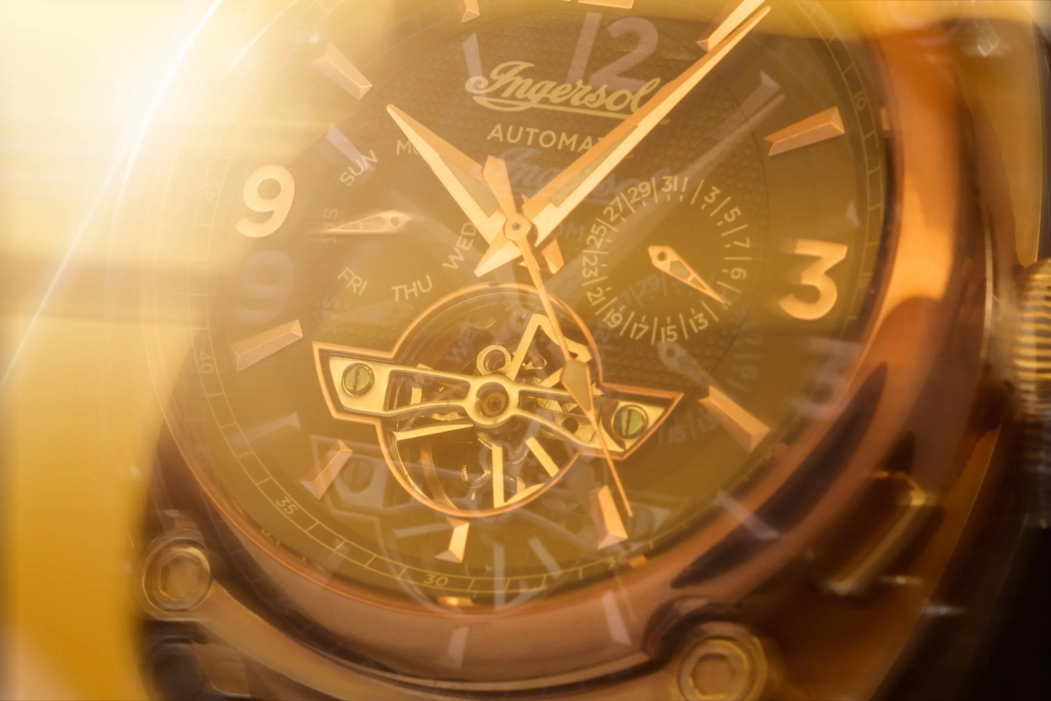 Close-up of a gold-toned Ingersoll automatic wristwatch with multiple dials and visible mechanical components.