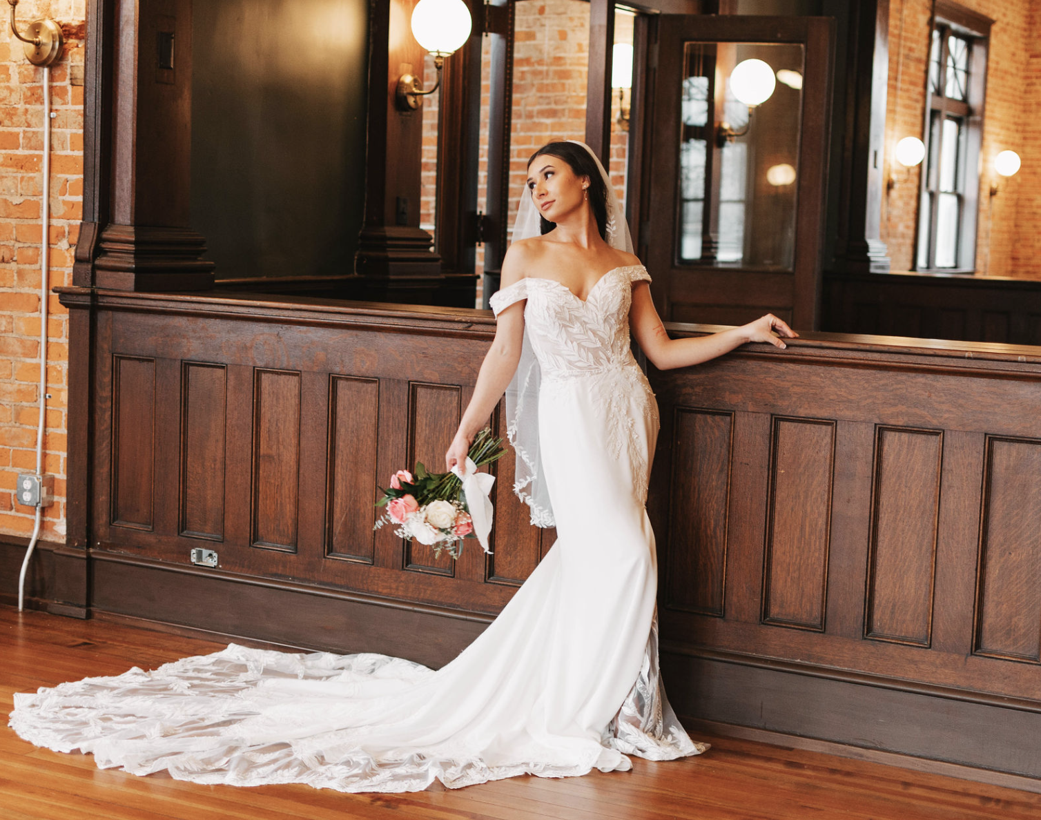 A bride standing along stained book case entry to library