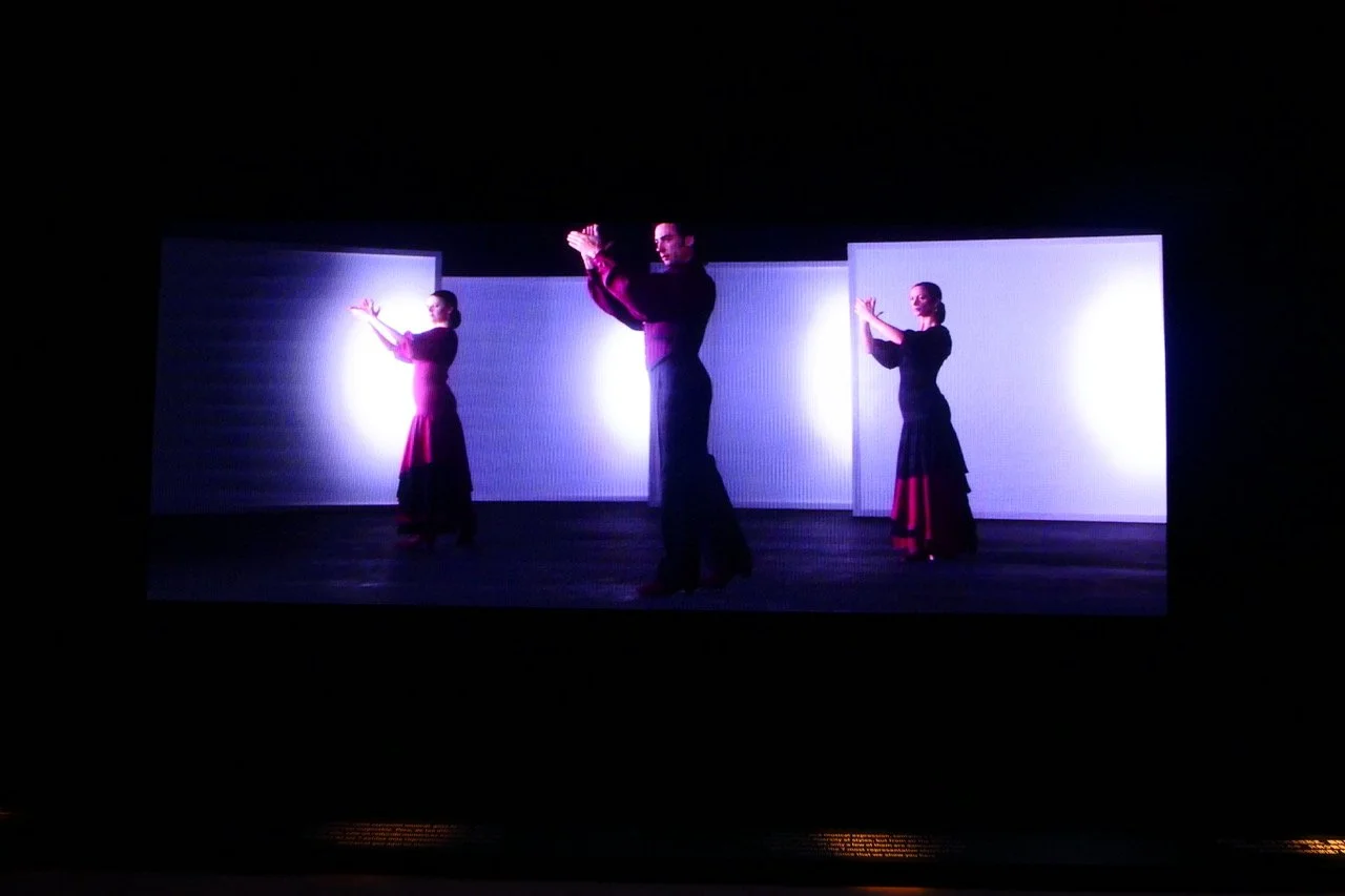 Two female flamenco dancers and one male flamenco dancer performing on stage