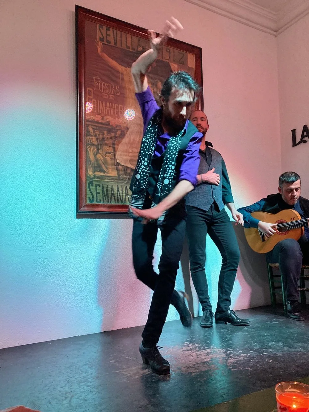 Male flamenco dancer dancing on stage with a guitarist accompanying him