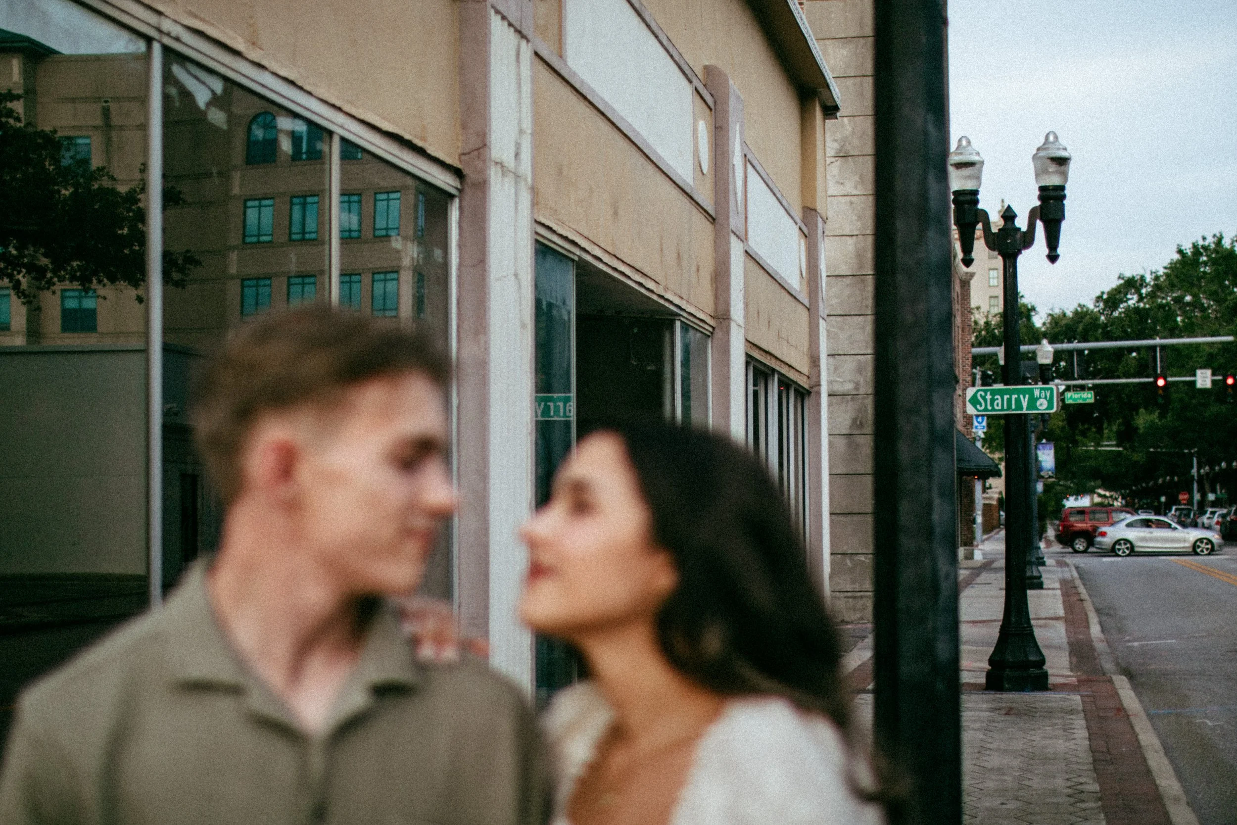 Blurred image of a man and woman standing on a city sidewalk facing each other with a building and street signs reading 'Starry Way' in the background.
