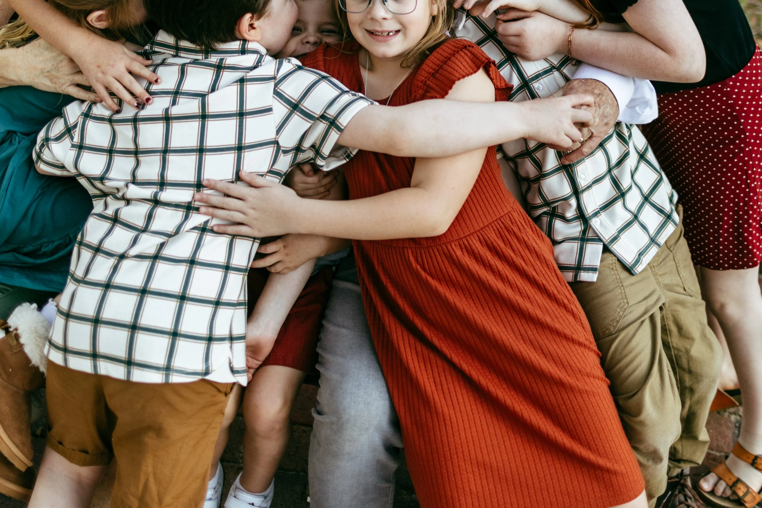 Group of children and adults hugging each other closely.