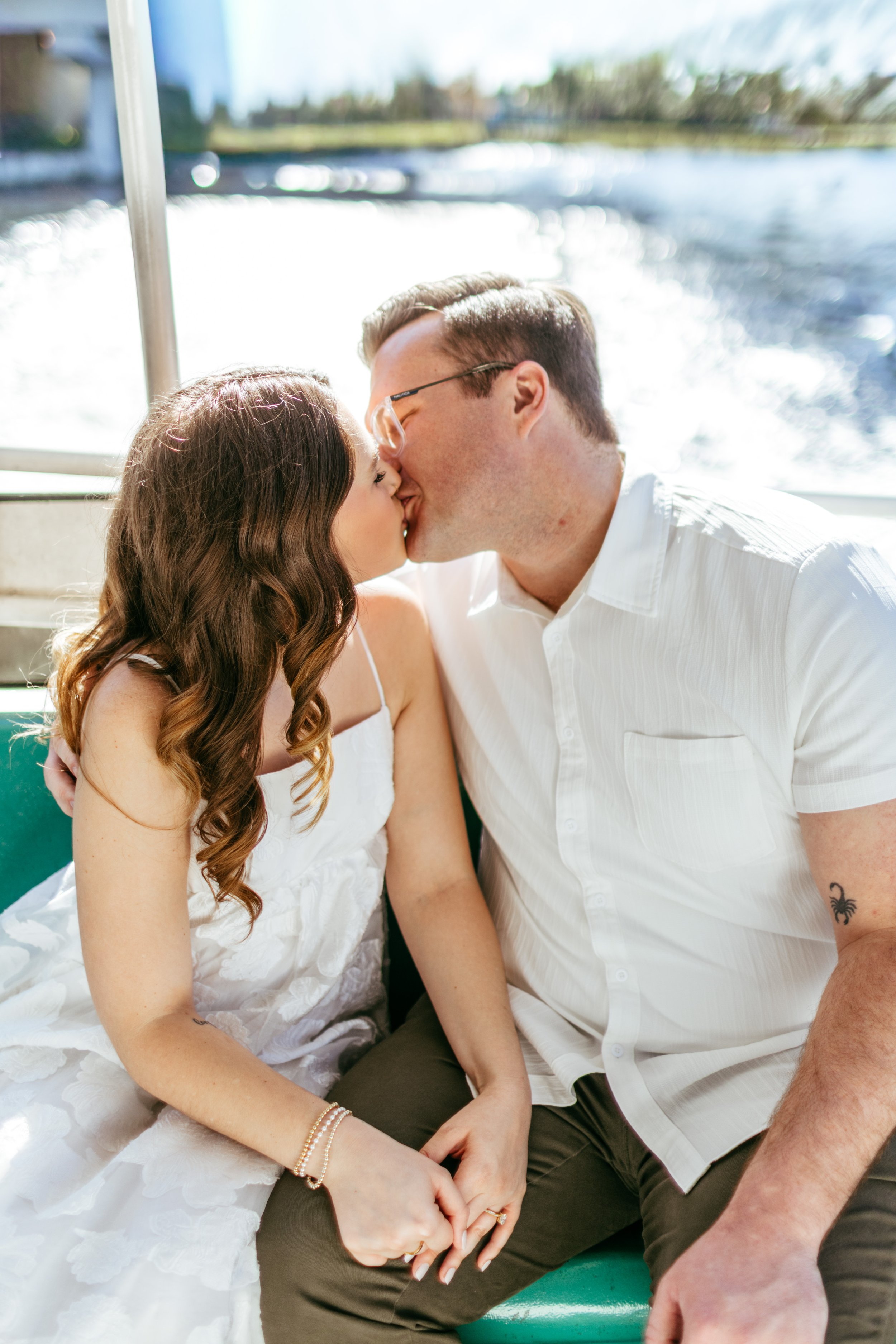 A couple kissing on a boat with water in the background.