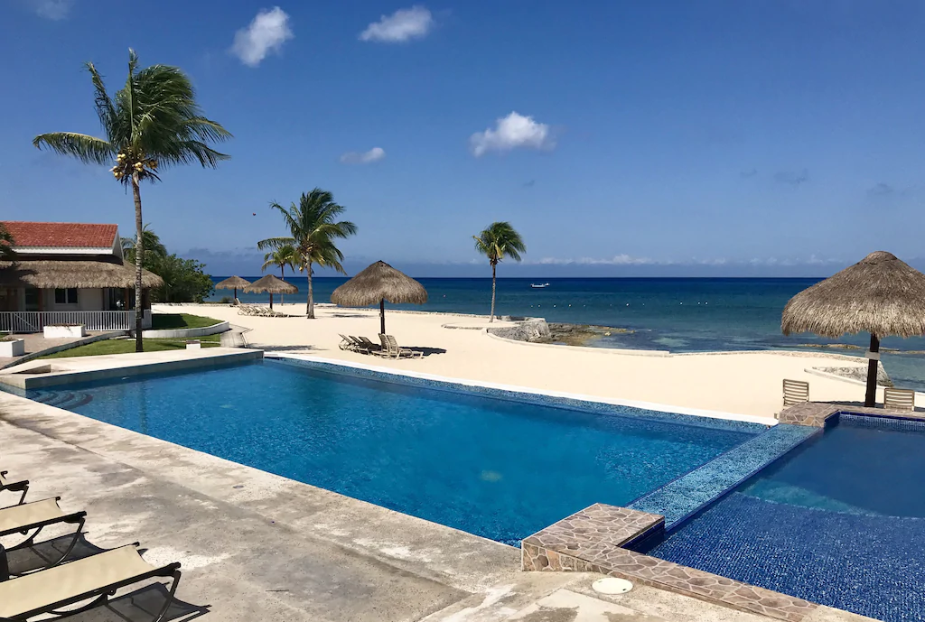 Infinity pool, palm trees, and Caribbean Sea view at the Costa del Sol oceanfront community in Cozumel