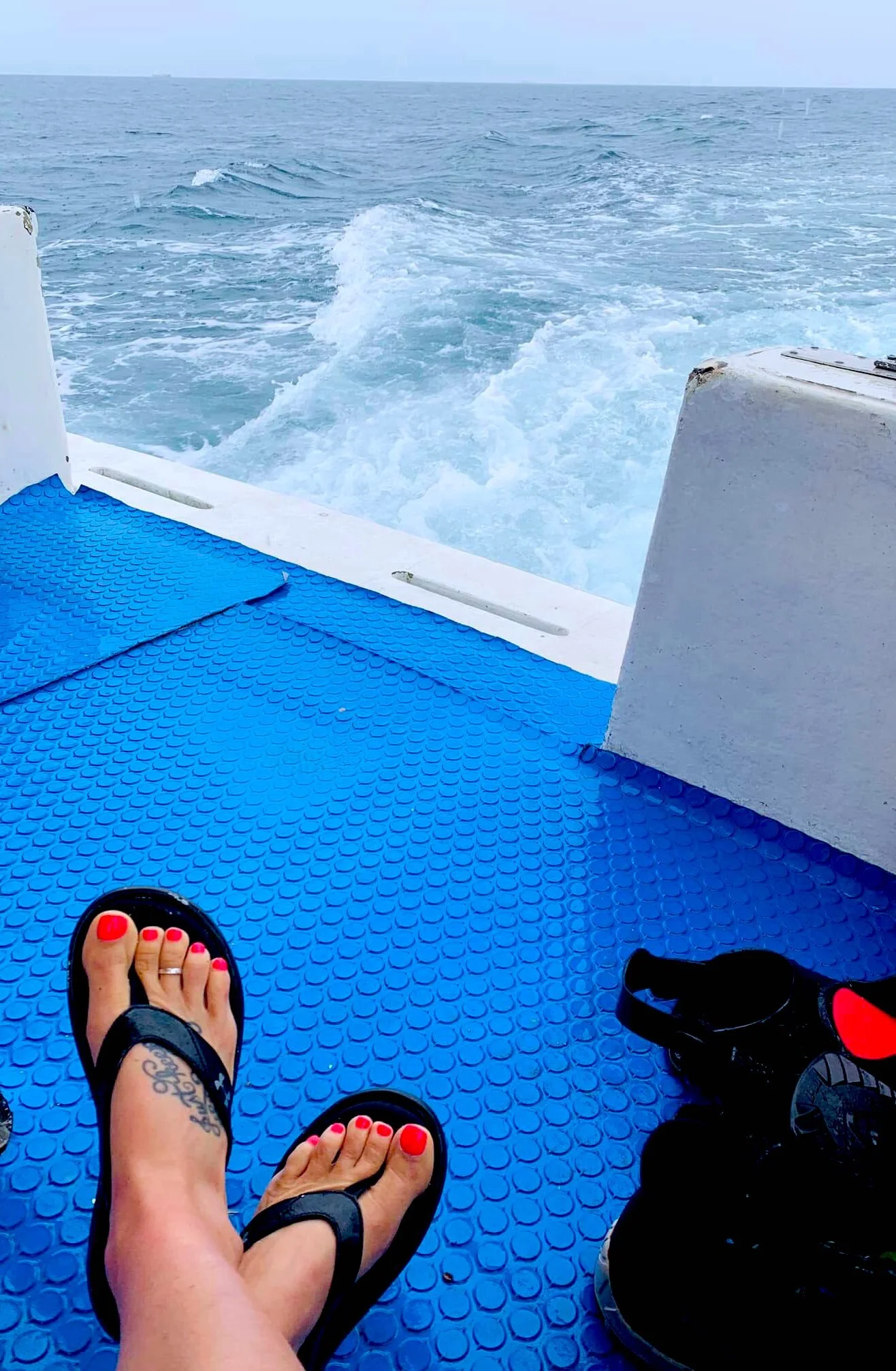 Dory's "Just Keep Swimming" tattooed feet resting on a dive boat before another scuba diving adventure in Cozumel, Mexico.