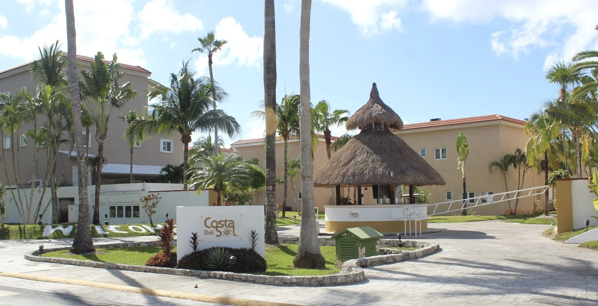 Tropical welcome to Costa del Sol - Entrance to Costa del Sol community in Cozumel  -  palm trees, a thatched-roof palapa, and island charm greet guests arriving at Weโve Gone Coastal Villaโs gated community in Cozumel.
