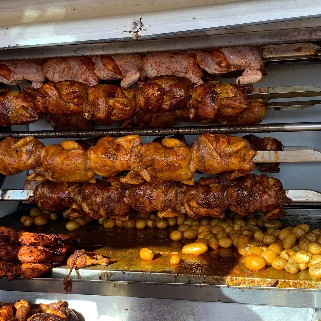 Rotisserie chickens roasting over baby potatoes at Rosticería El Pechugón in Cozumel