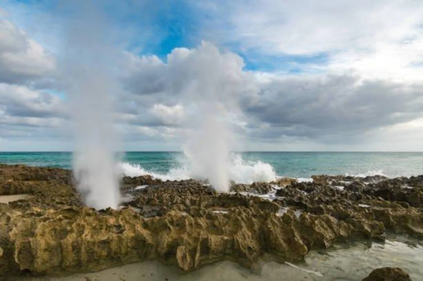 Blowholes on Cozumel's rugged east side coastline with waves crashing against the rocky shore.