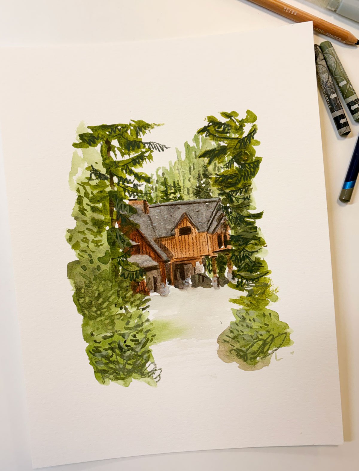 A small painting of Island Lake Lodge peeking through the trees in Fernie, BC by Brina Schenk