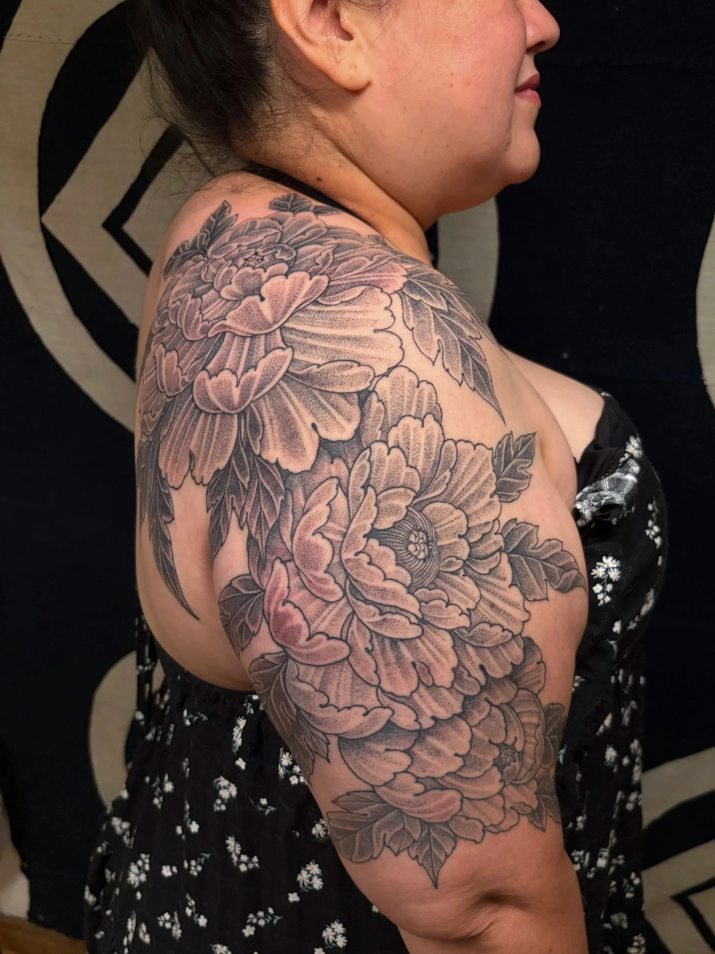 stipple shaded large scale peony flower tattoos wrapping around women's shoulder