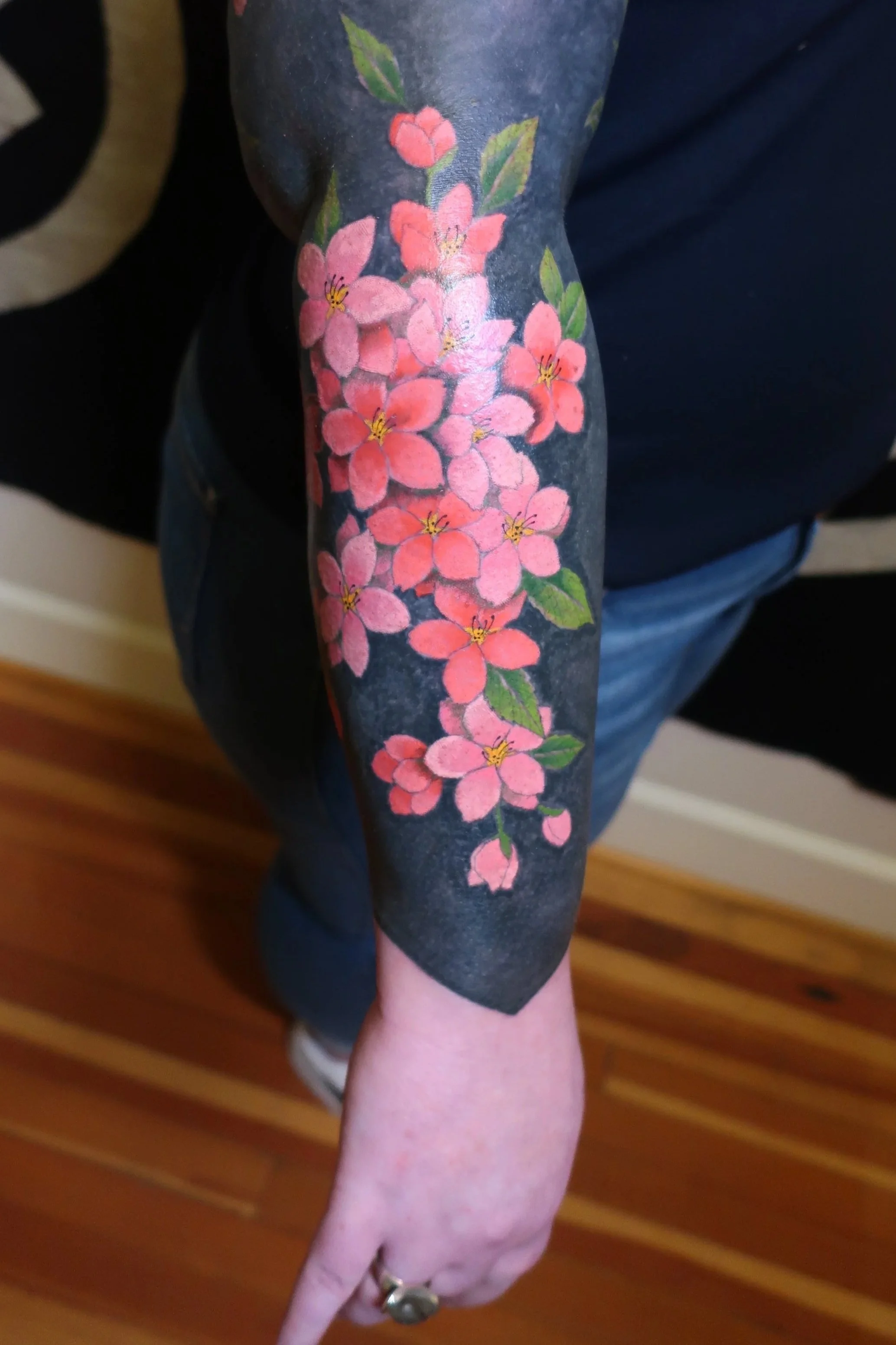 Blackwork background tattoo sleeve with feminine cherry blossoms in pinks and reds