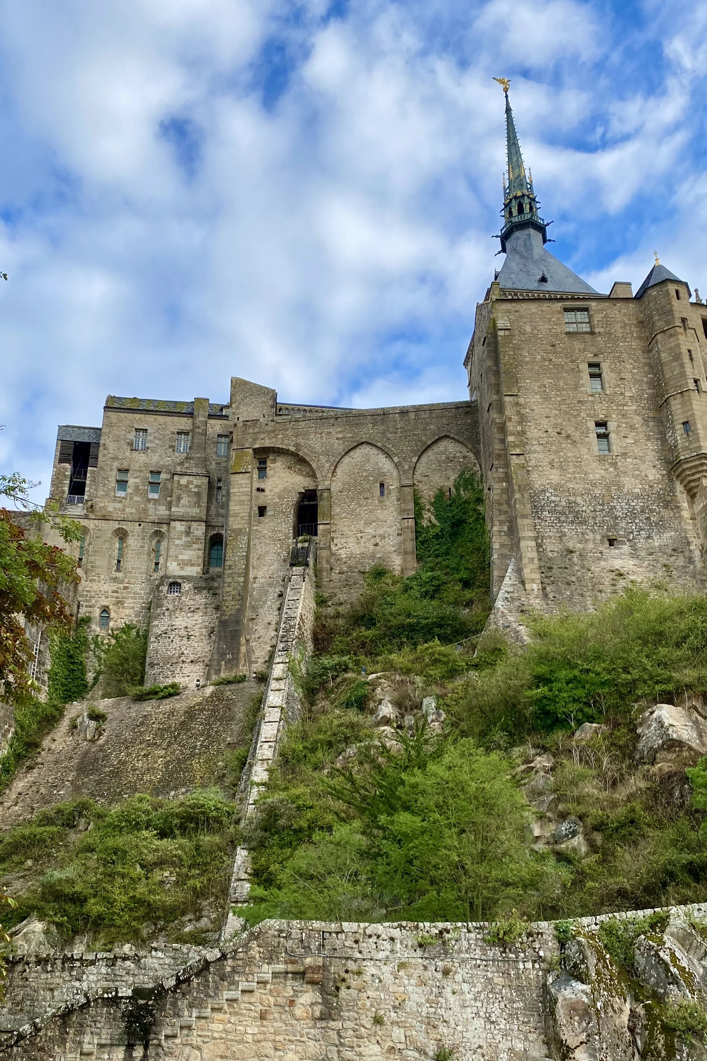 Mont Saint-Michel Abbey rising dramatically above the rocky island in Normandy, its stone walls and soaring spire crowned by the statue of Saint Michael.