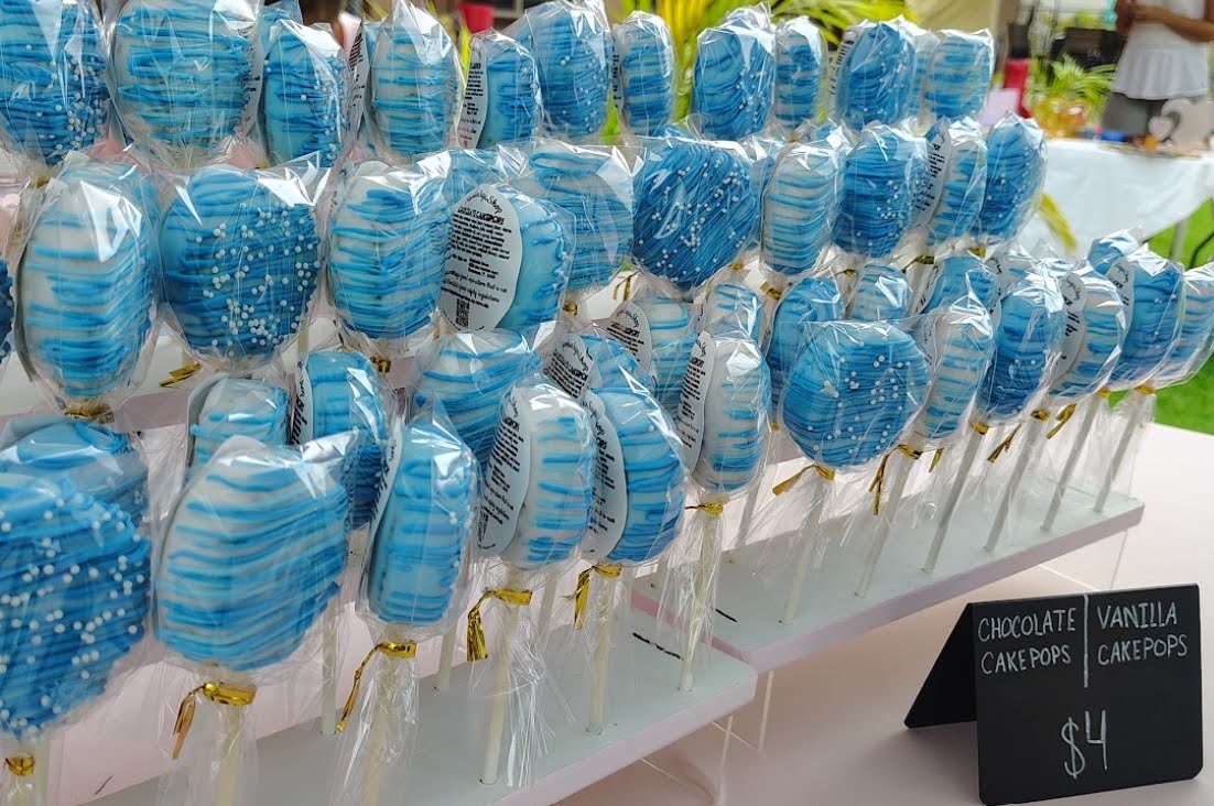 Blue and white striped cake pops decorated with white dots, wrapped in clear plastic, arranged on a display table at a  Kissimmee Main Street market
