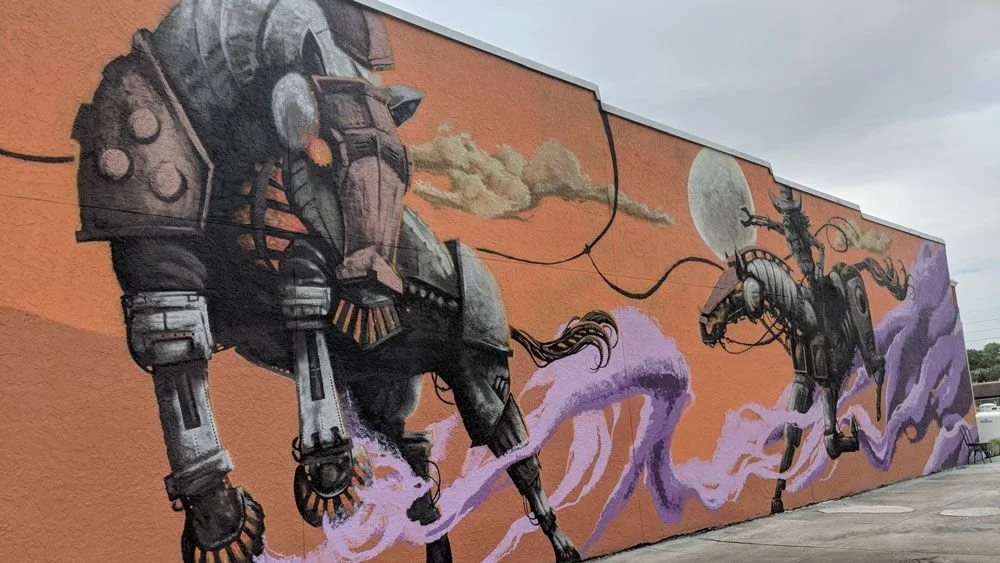 An Image of the Kowtown Mural on Broadway Kissimmee Florida. Depicts a futuristic cowboy and horse.