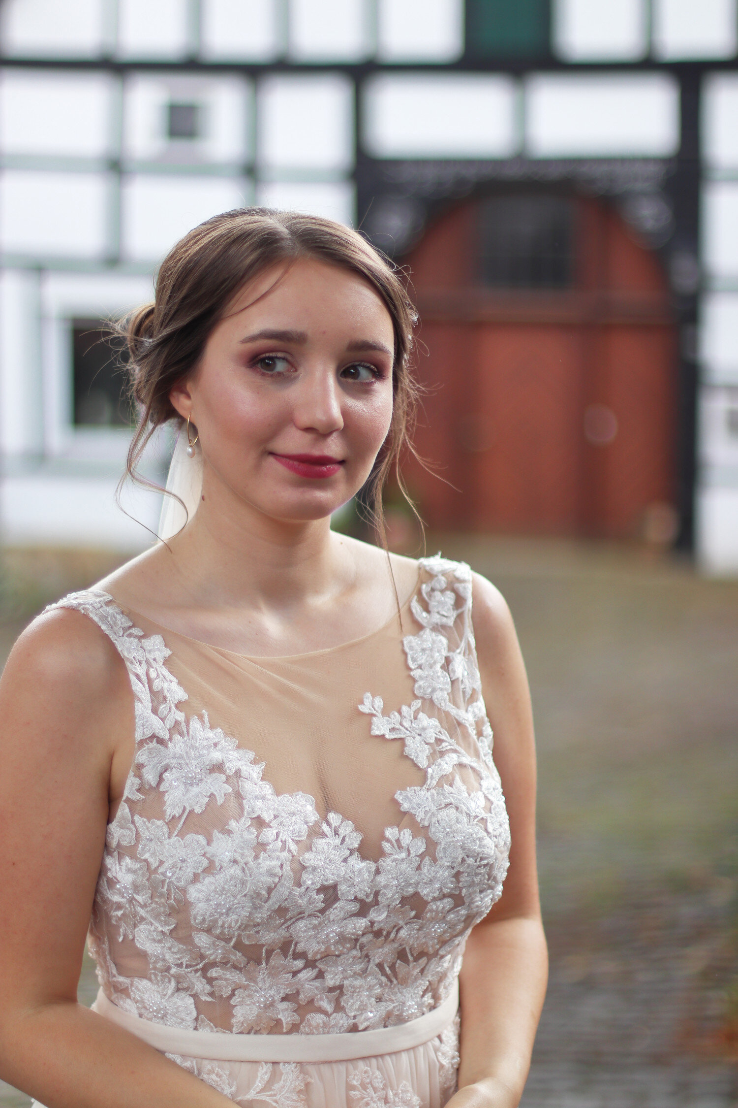 Dieses Foto zeigt Jutta in ihrem Brautkleid vor einem alten Fachwerkhaus.