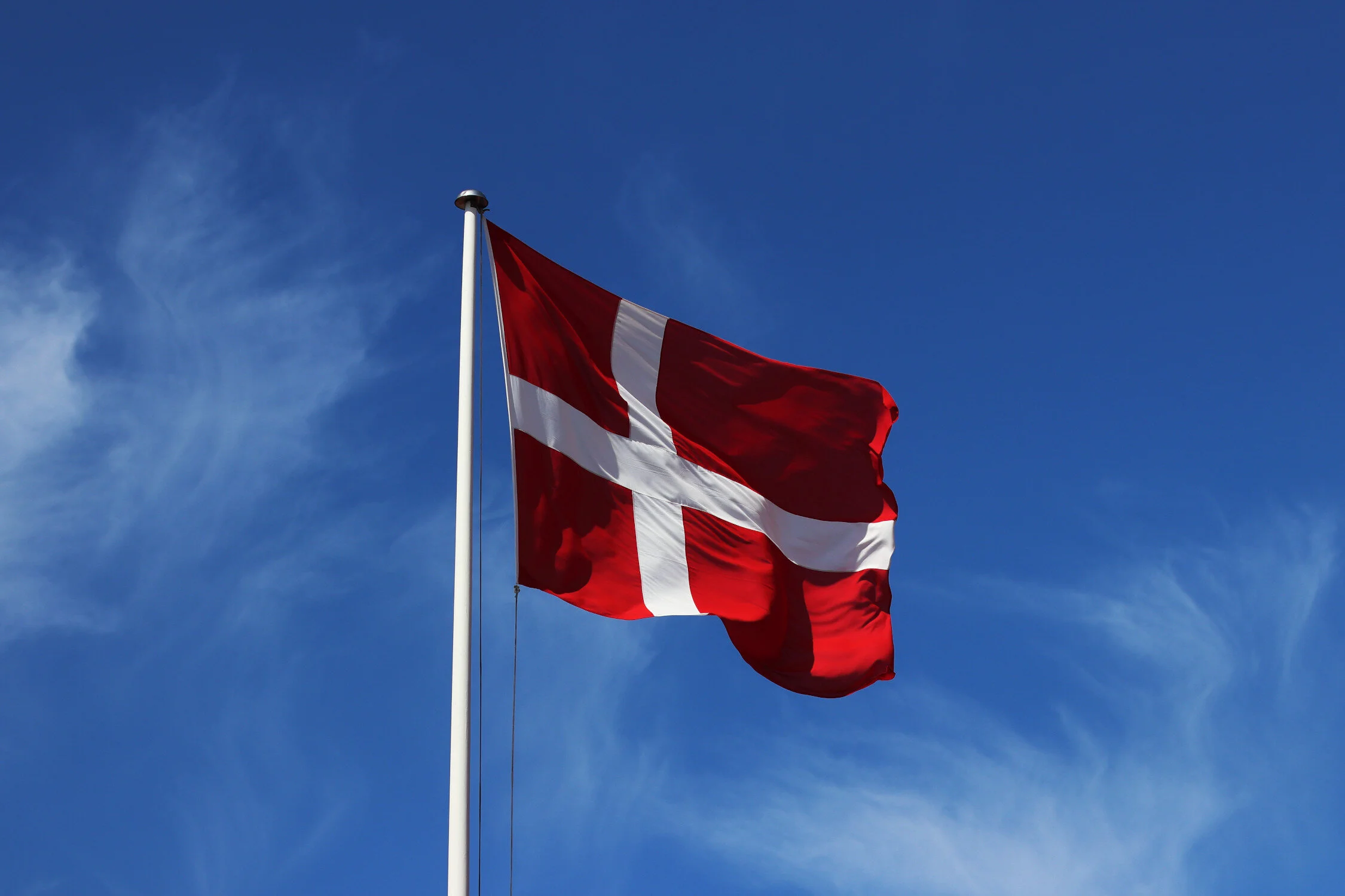 Dieses Foto zeigt die dänische Flagge vor blauem Himmel in Dänemark.