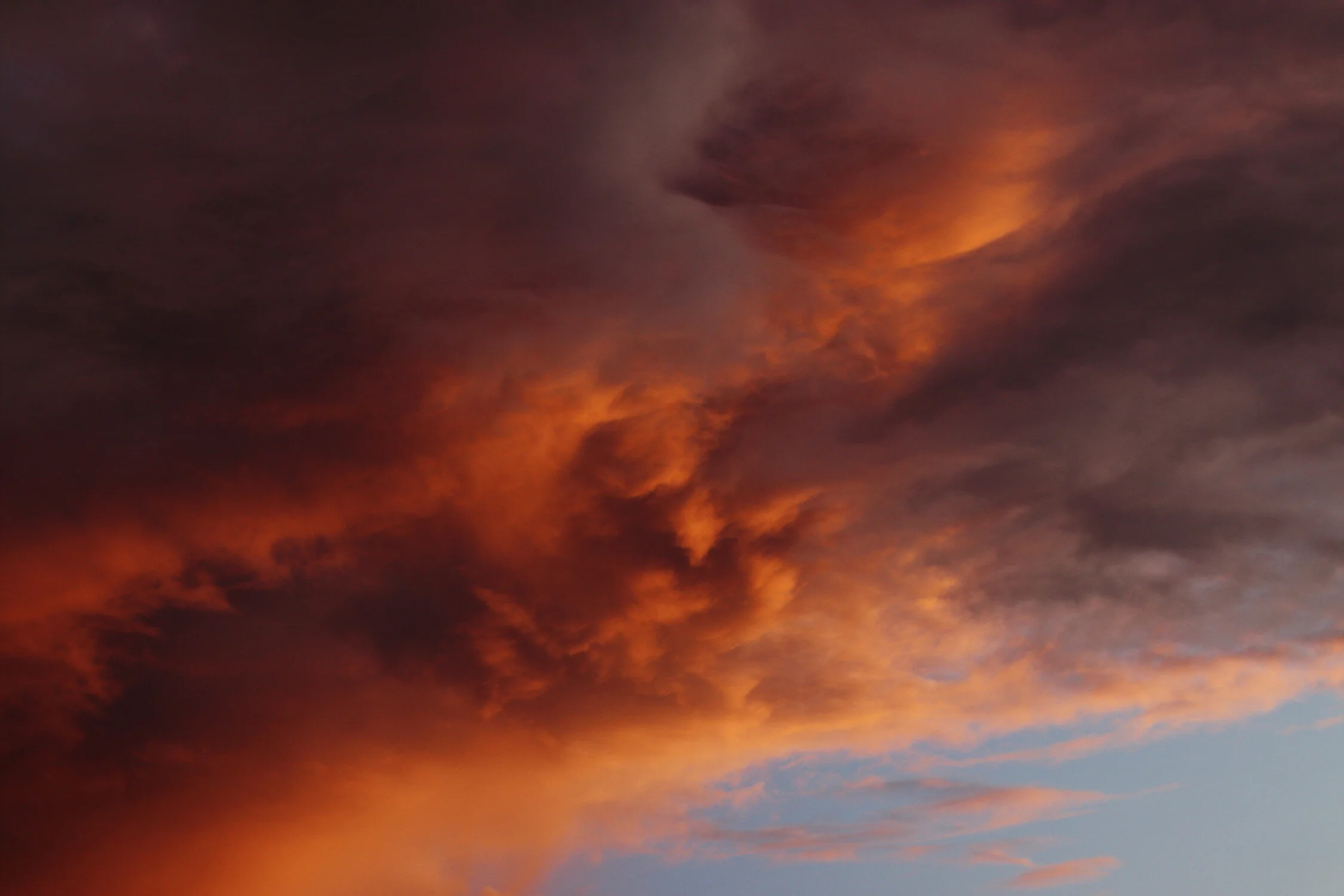 Dieses Foto zeigt eine vom Sonnenuntergang orange und violett angestrahlte Wolke.
