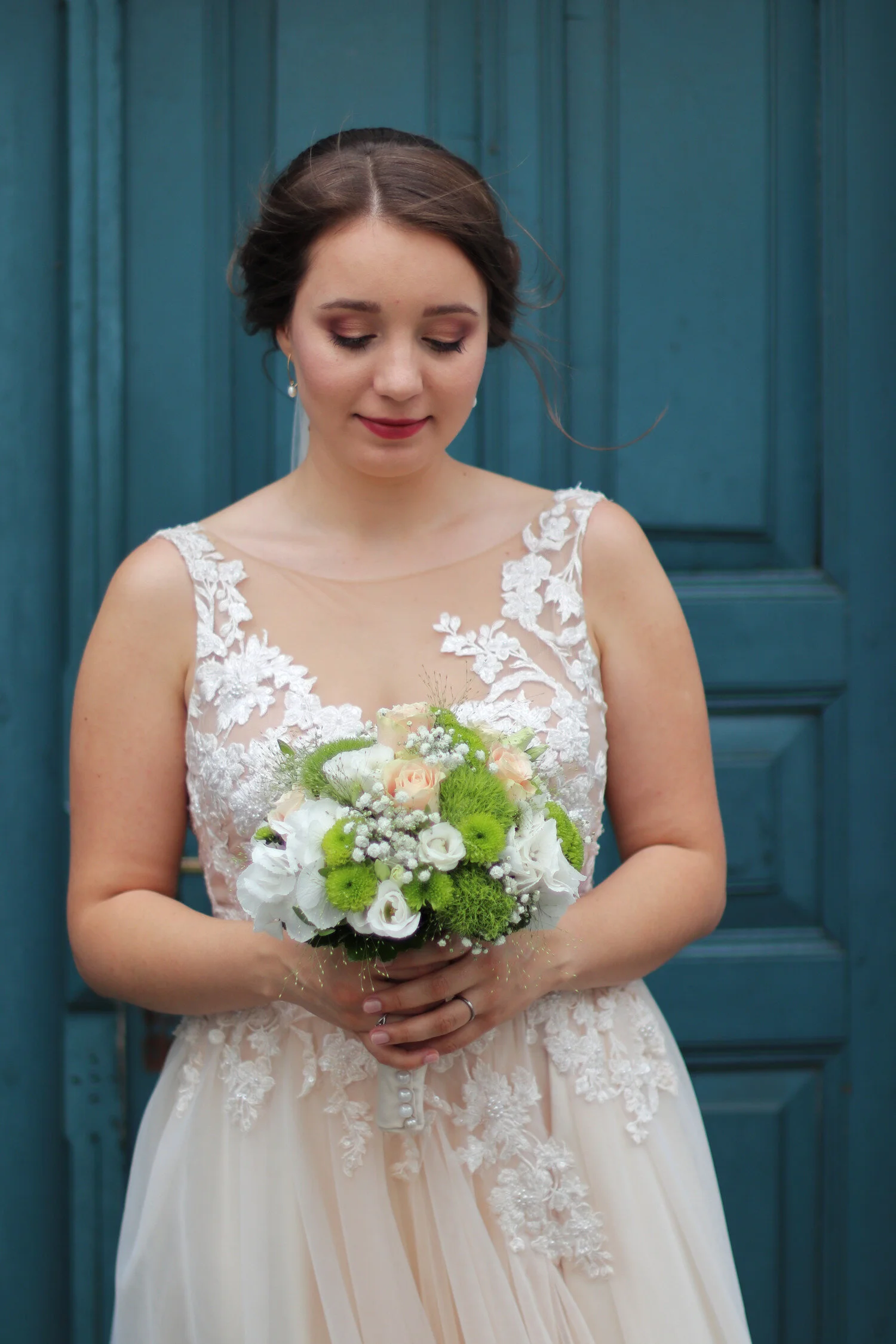Dieses Foto zeigt Jutta in ihrem Brautkleid vor einer blauen Holztür.