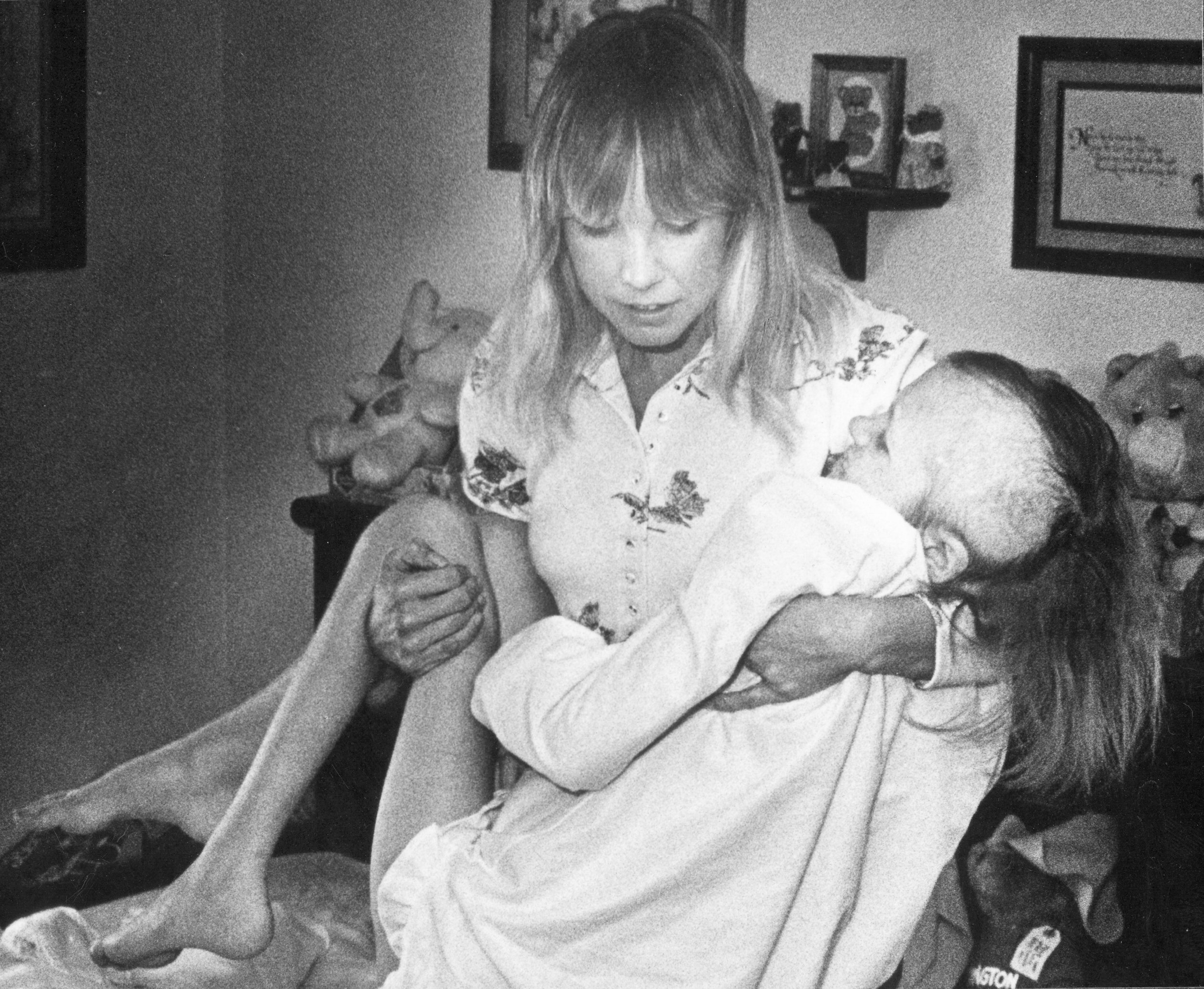 A woman carries her dying daughter.